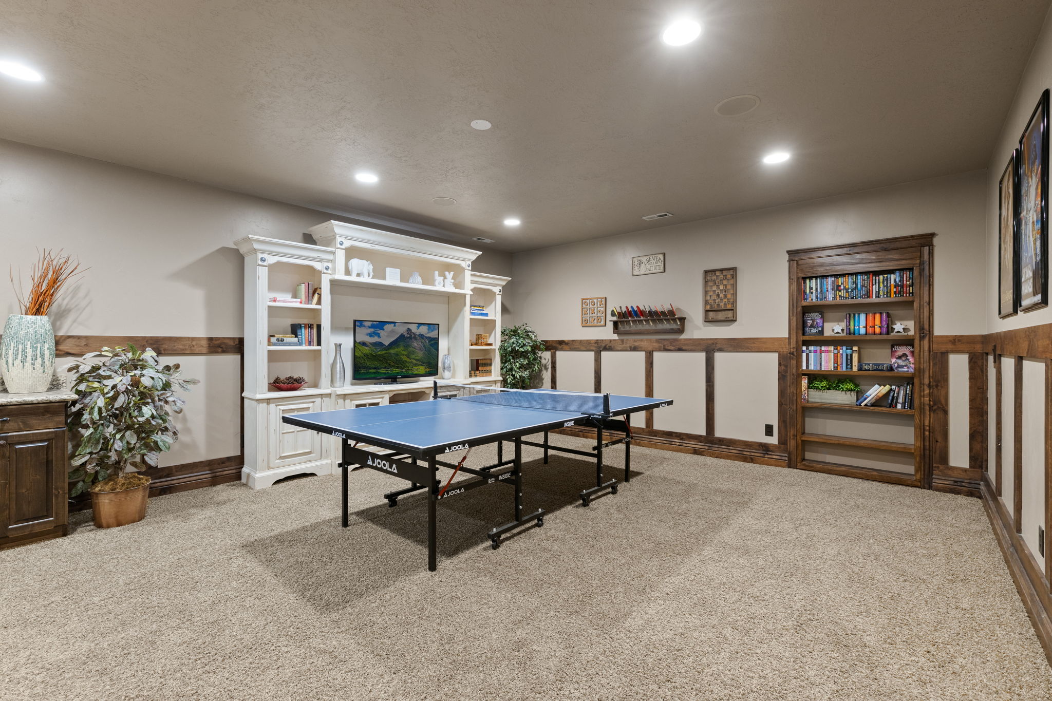 Finished room featuring recessed lighting, paneled walls with wood trim, a built-in entertainment center, and a built-in bookcase