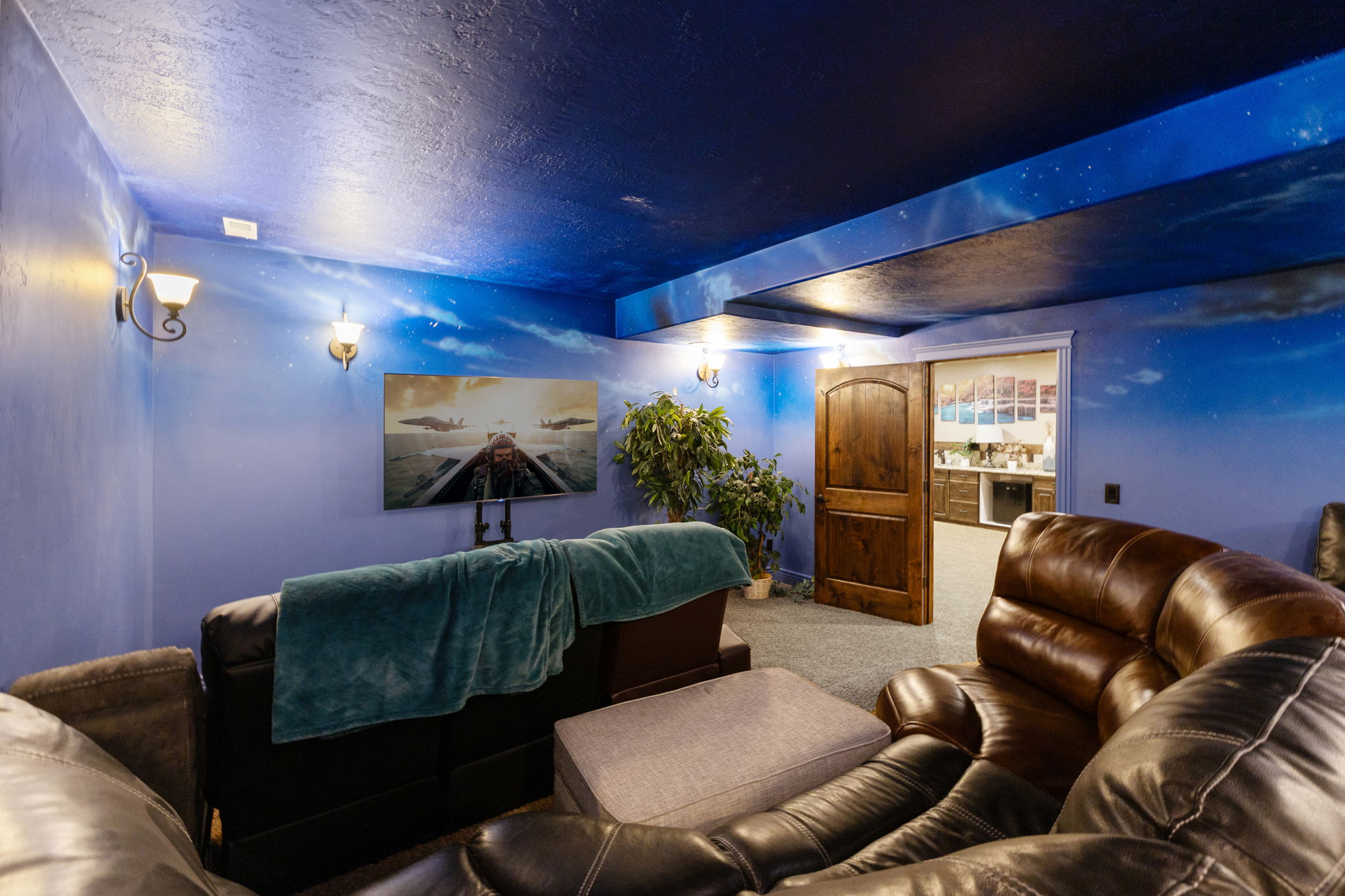Entertainment space featuring a custom painted ceiling and walls, sconce lighting, and a wood-panel door