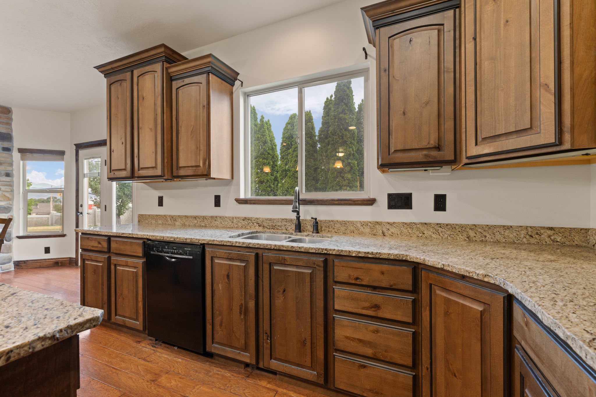 Kitchen featuring wood-finish cabinetry, granite countertops, and a double basin sink with a matte black faucet