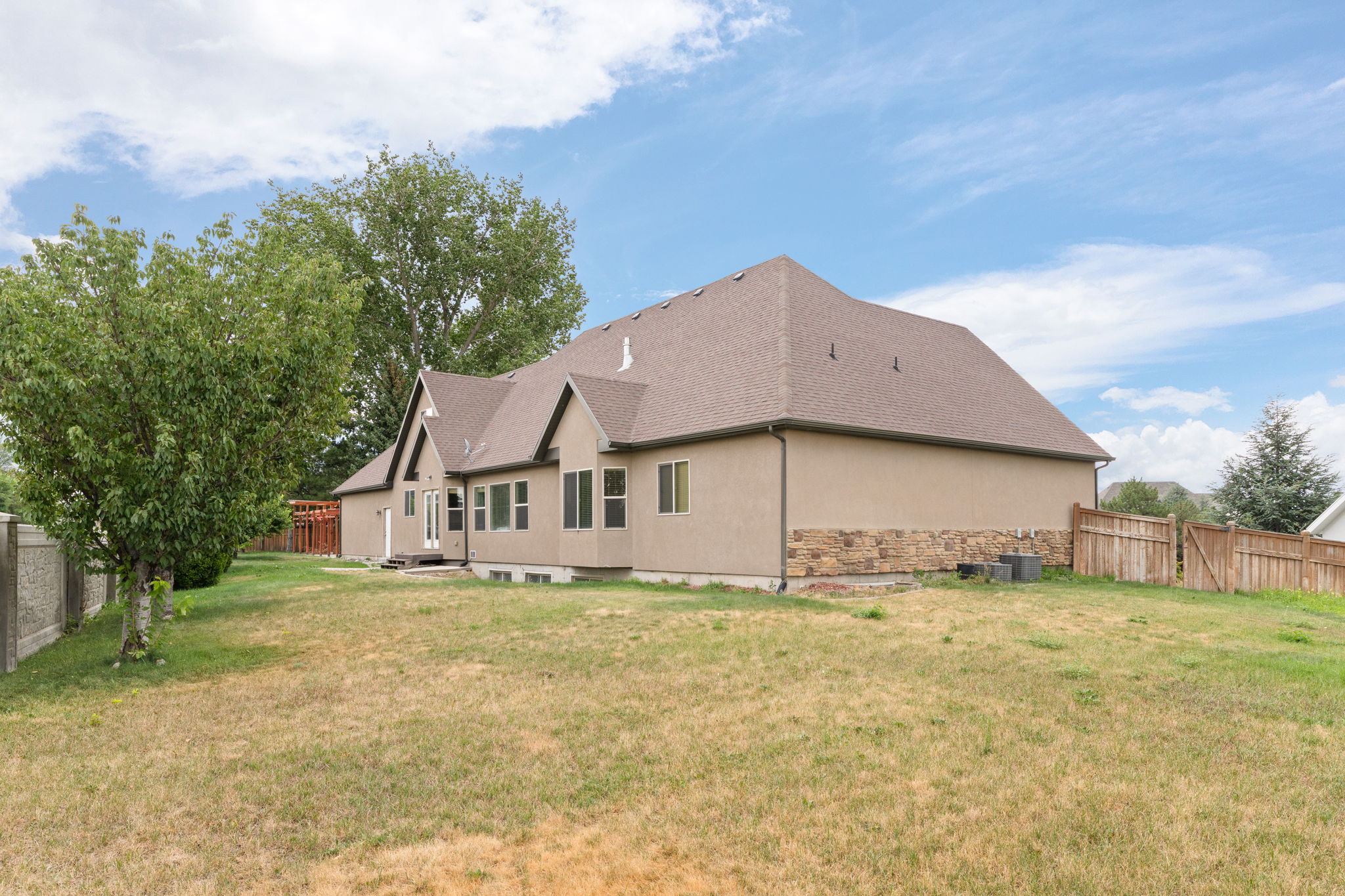 Rear exterior featuring a neutral stucco finish with stone veneer accents