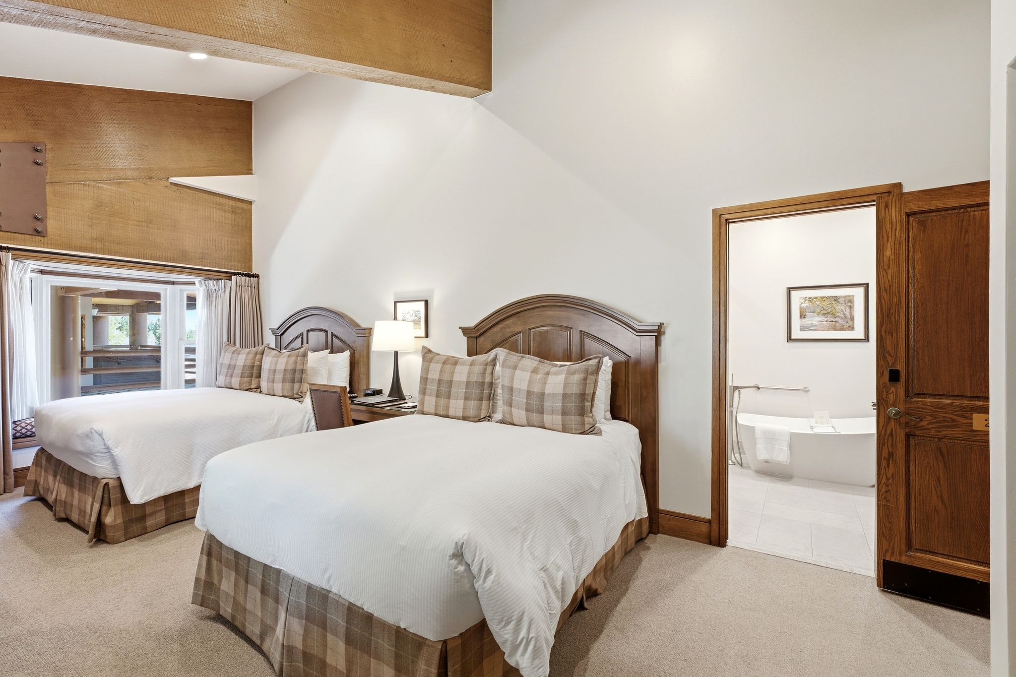 Bedroom featuring vaulted ceilings, exposed wood beams, and a window seat