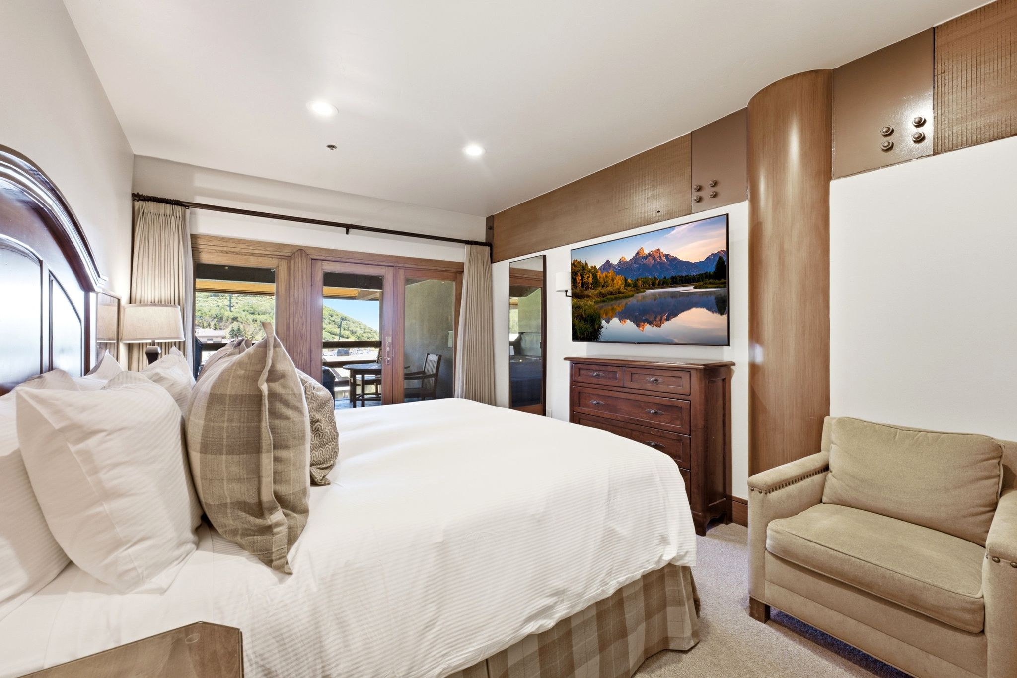 Light-filled bedroom featuring a wood-finish headboard, recessed lighting, and direct access to a private outdoor patio through double glass doors