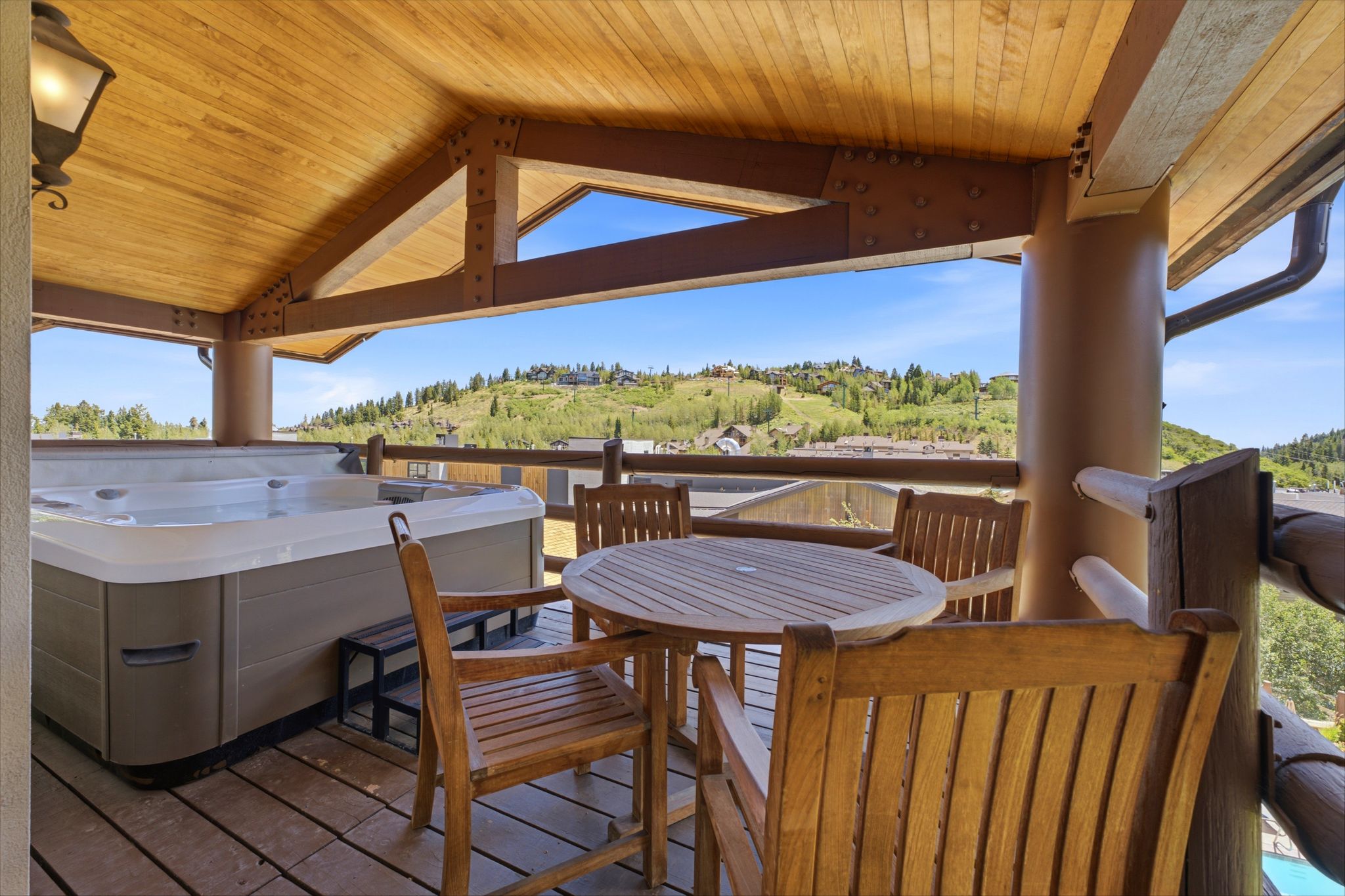 Expansive covered deck featuring a built-in hot tub and wood-finish flooring