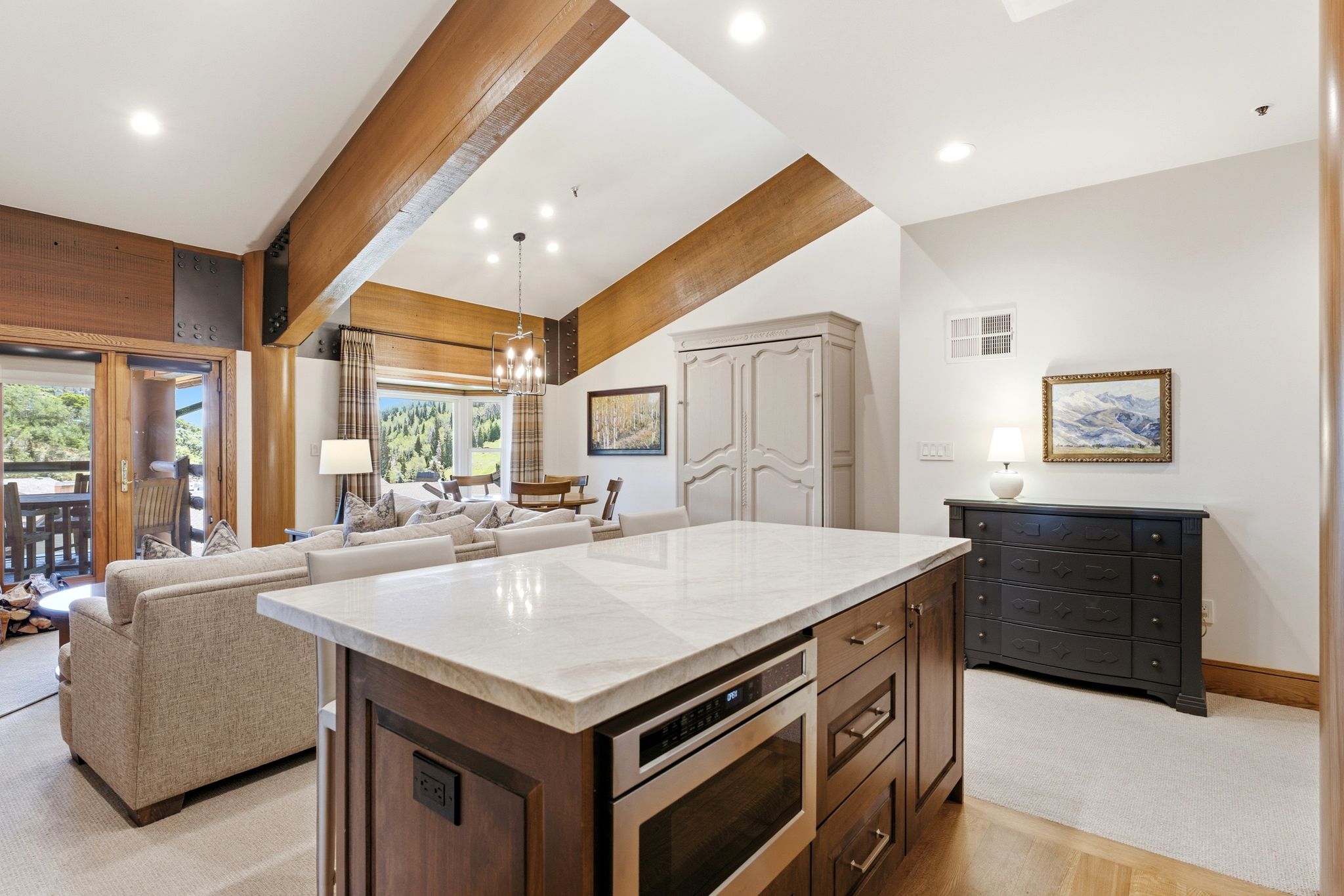 Kitchen island featuring a white stone countertop, built-in microwave, and wood-finish cabinetry