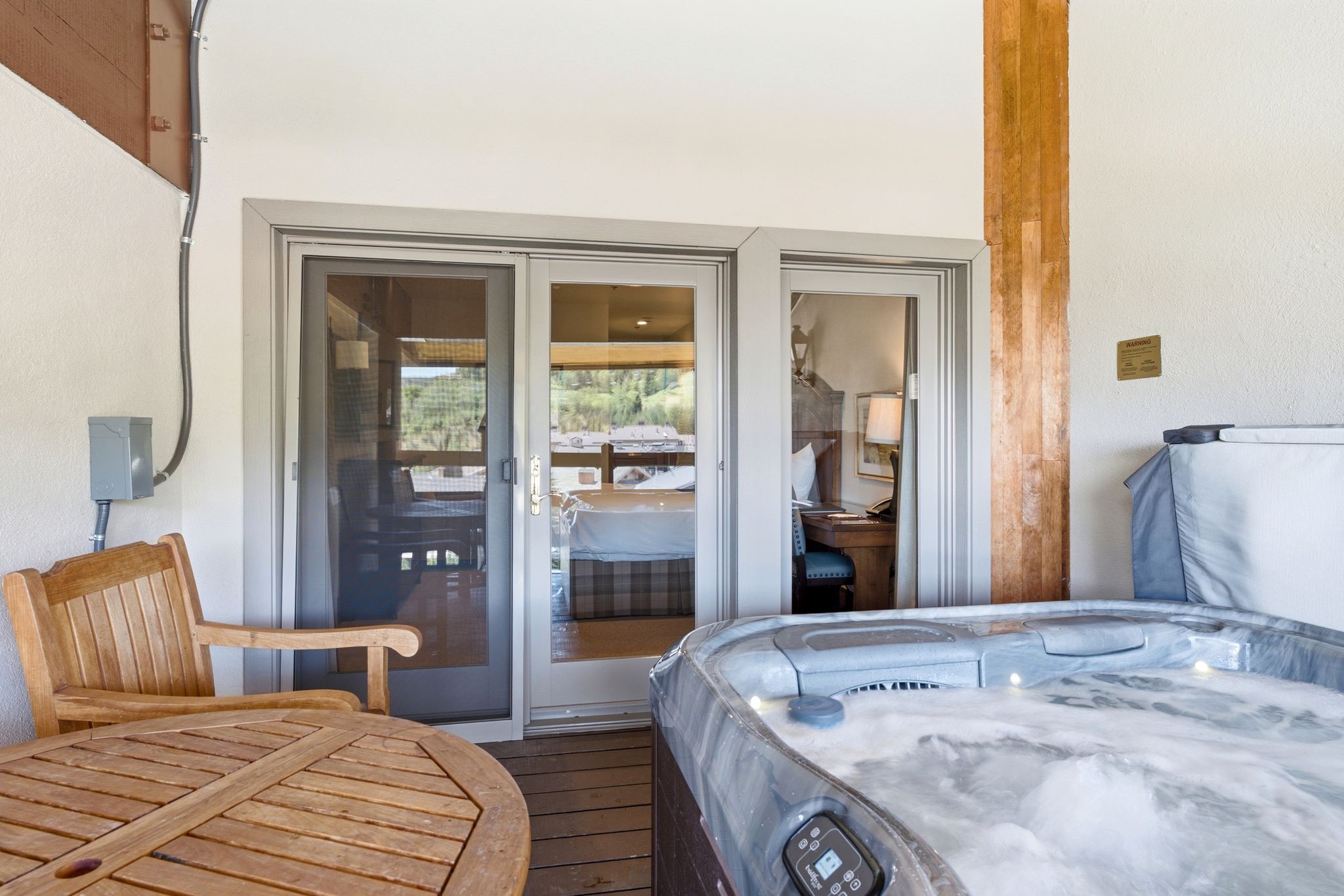 Outdoor deck featuring a built-in hot tub, wood-finish flooring, and a sliding glass door entry