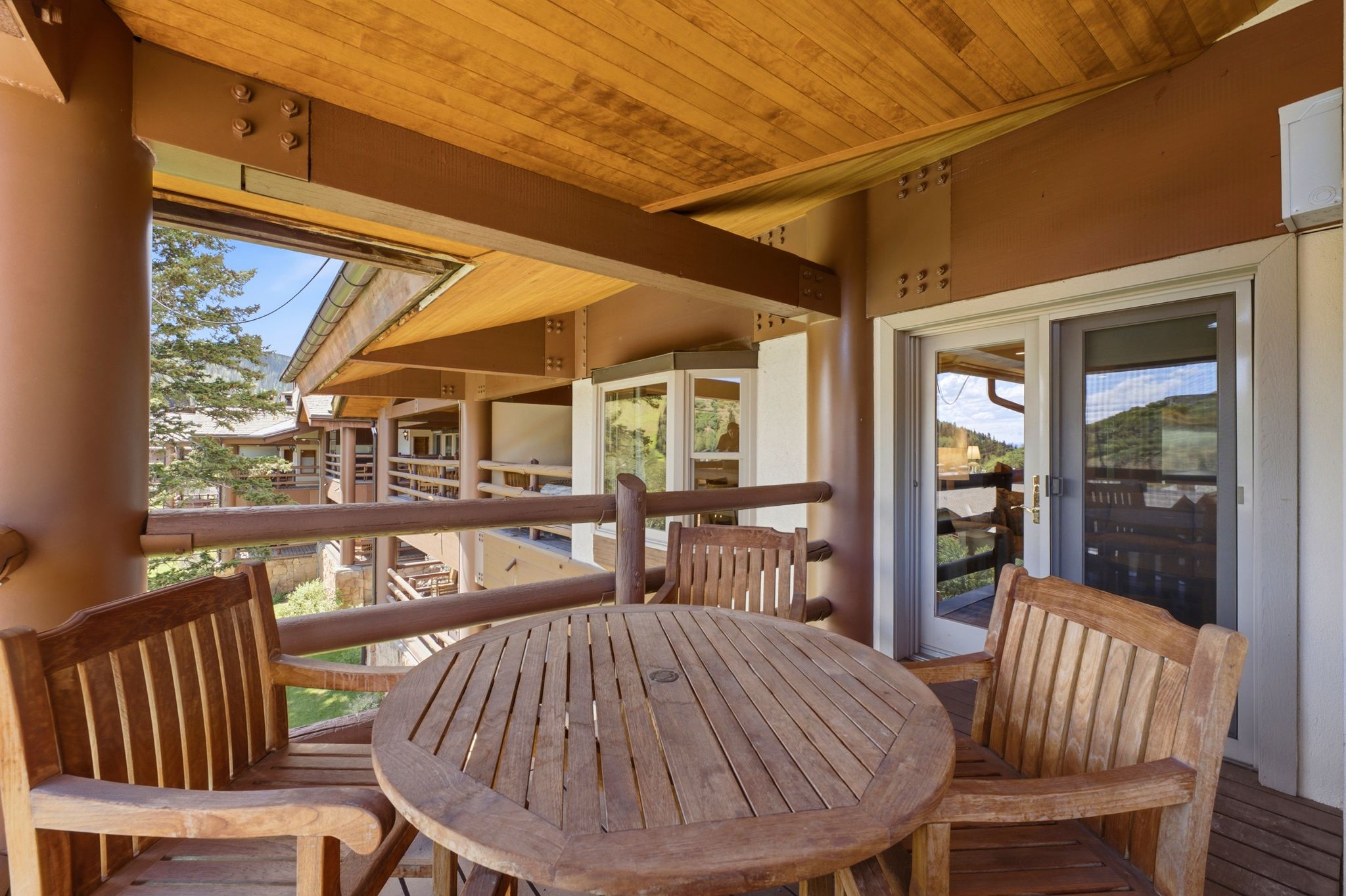 Covered balcony featuring a wood-finish ceiling, exposed structural beams, and a wood-slat deck