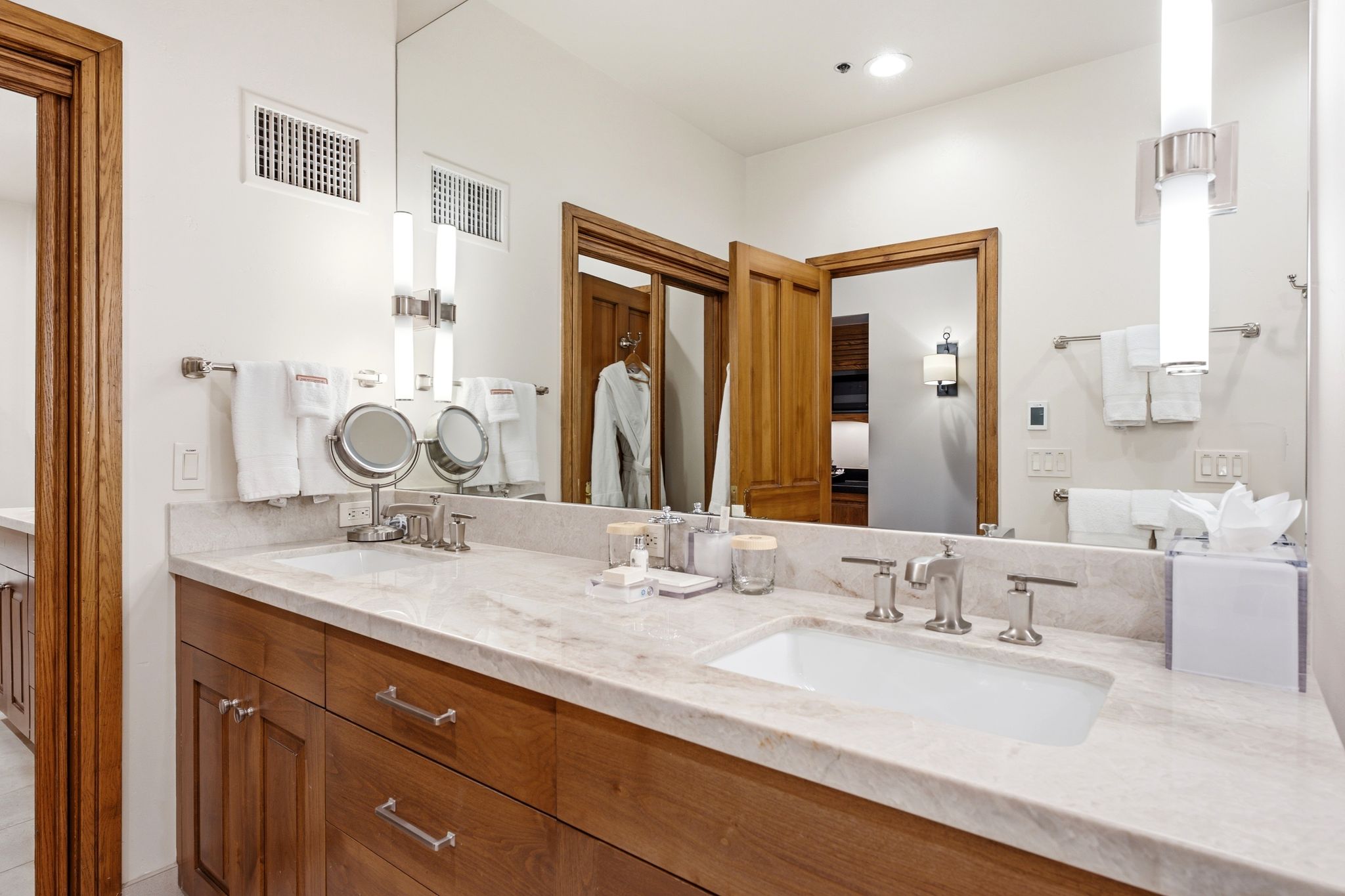 Double vanity with an integrated rectangular sink, light-toned stone countertop, and wood-finish cabinetry