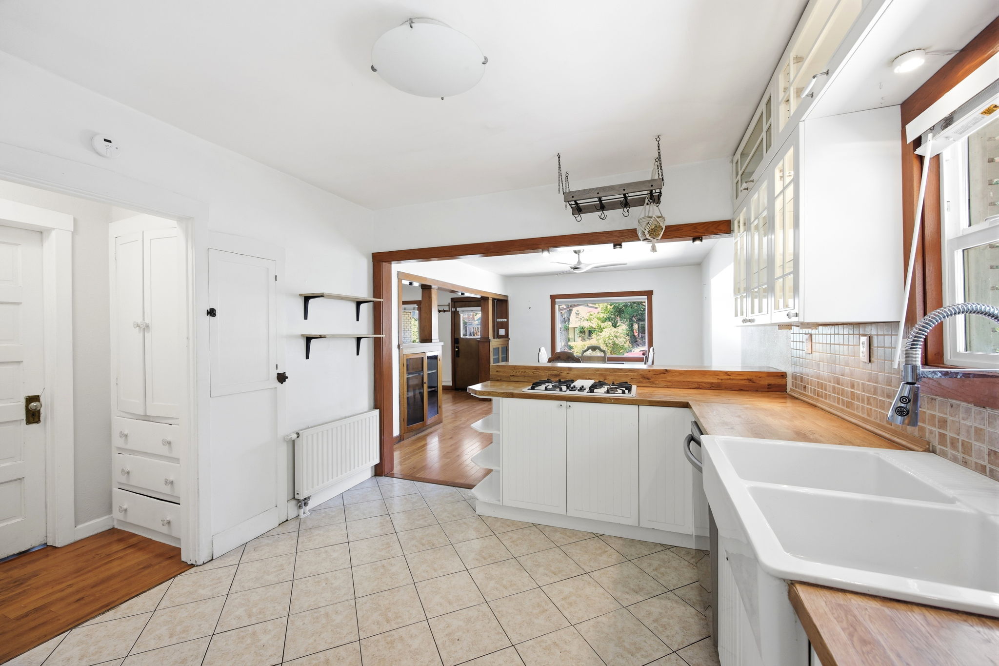 Kitchen featuring white cabinetry, butcher block countertops, a double basin farmhouse sink, and tile flooring