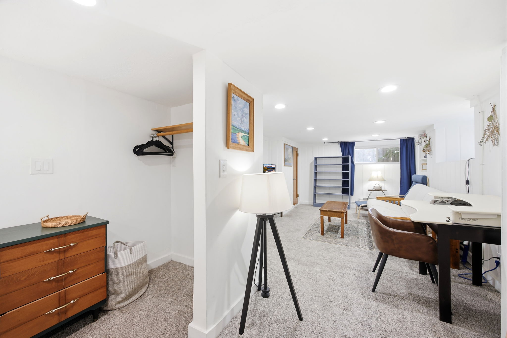 Spacious room featuring light gray carpeting, recessed lighting, and a window with blue drapes