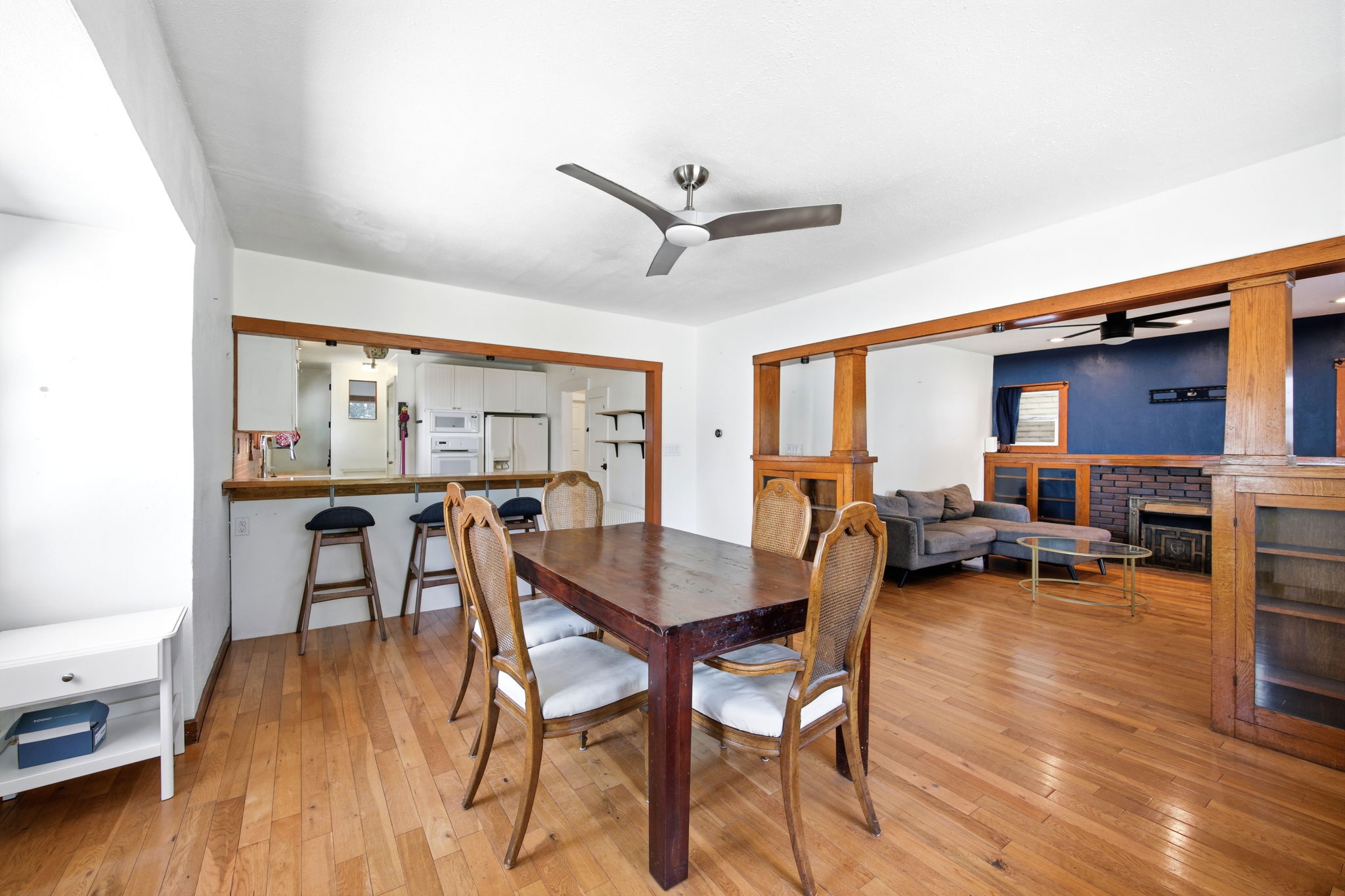 Open-concept living space featuring wood-finish flooring, a contemporary ceiling fan, and a pass-through breakfast bar with a wood-finish countertop