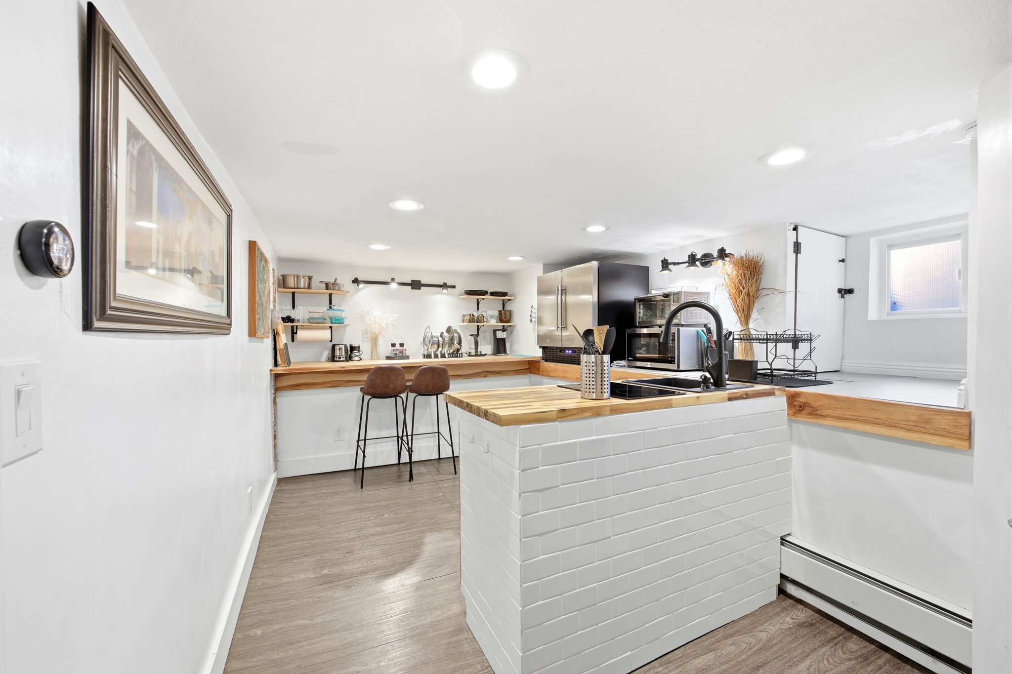 Modern kitchen space featuring a butcher block countertop, stainless steel appliances, recessed lighting, and wood-finish flooring