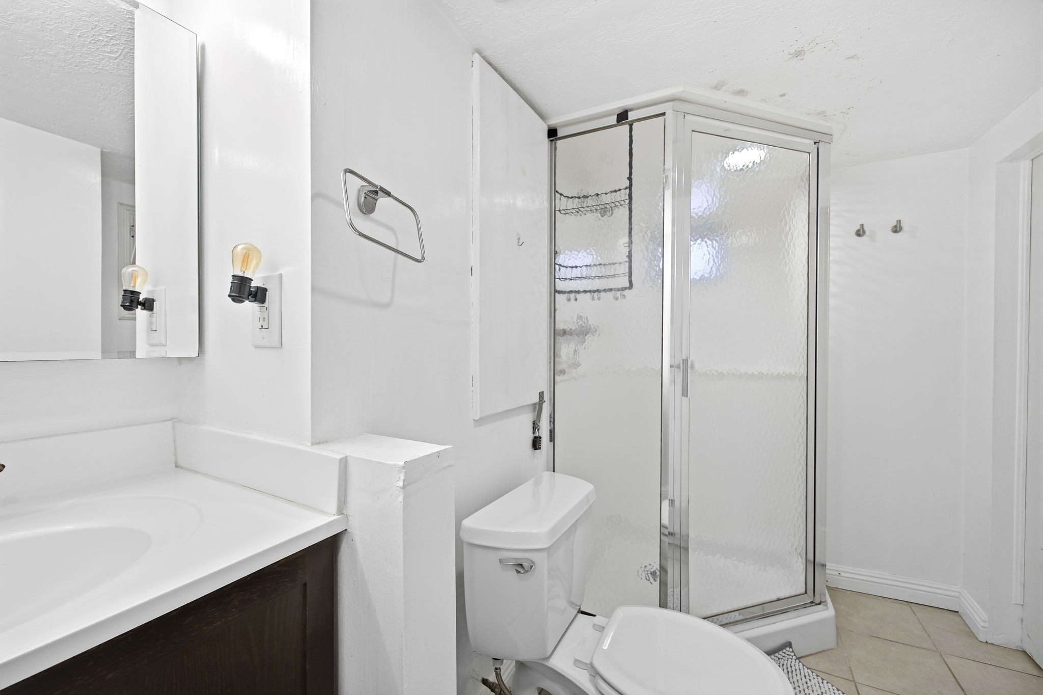 Bathroom featuring a glass-enclosed shower, white toilet, and a vanity with a white countertop and dark wood-finish cabinetry