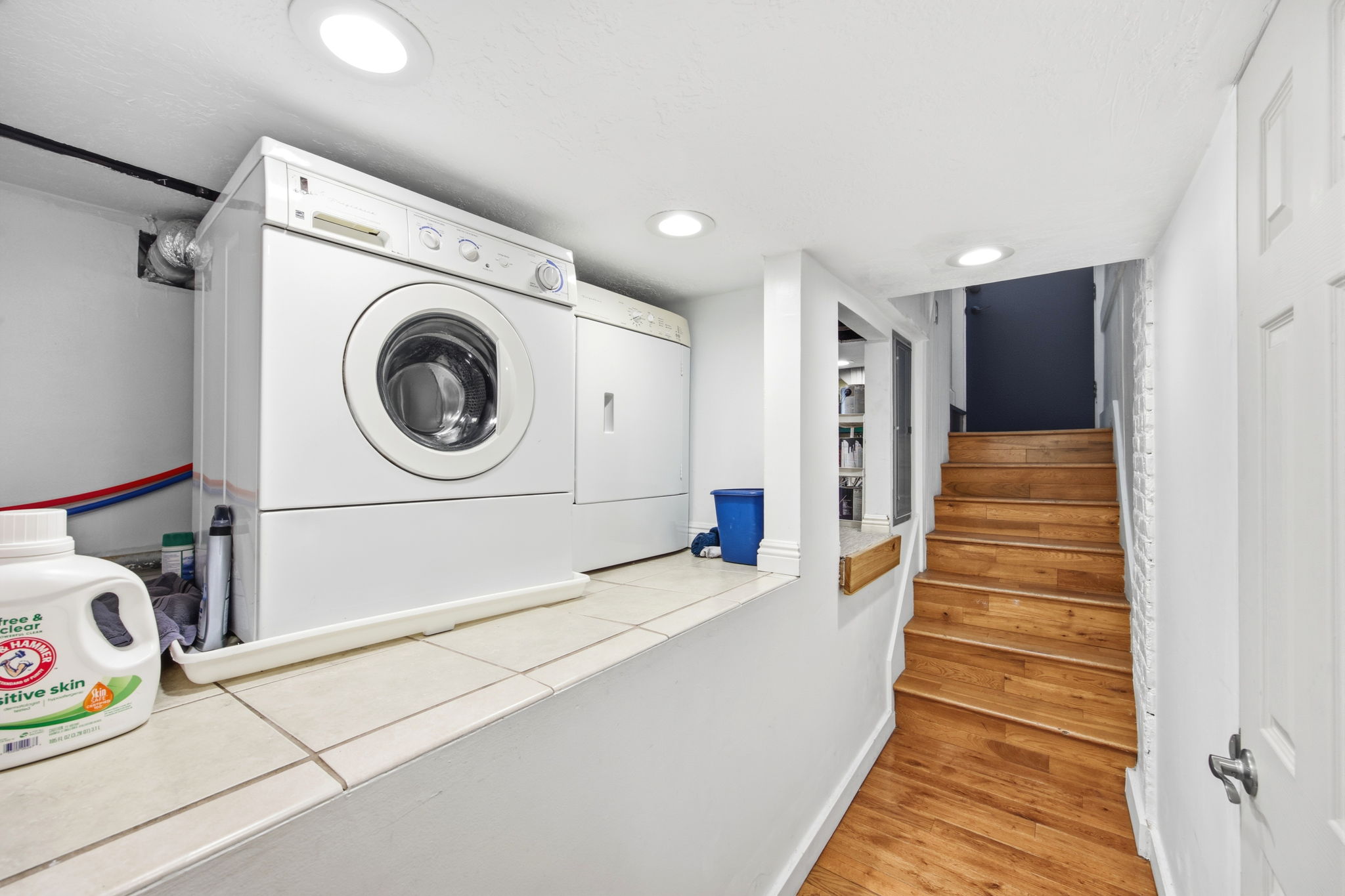 Dedicated laundry area featuring a front-load washer and dryer set, tiled countertop, and recessed lighting