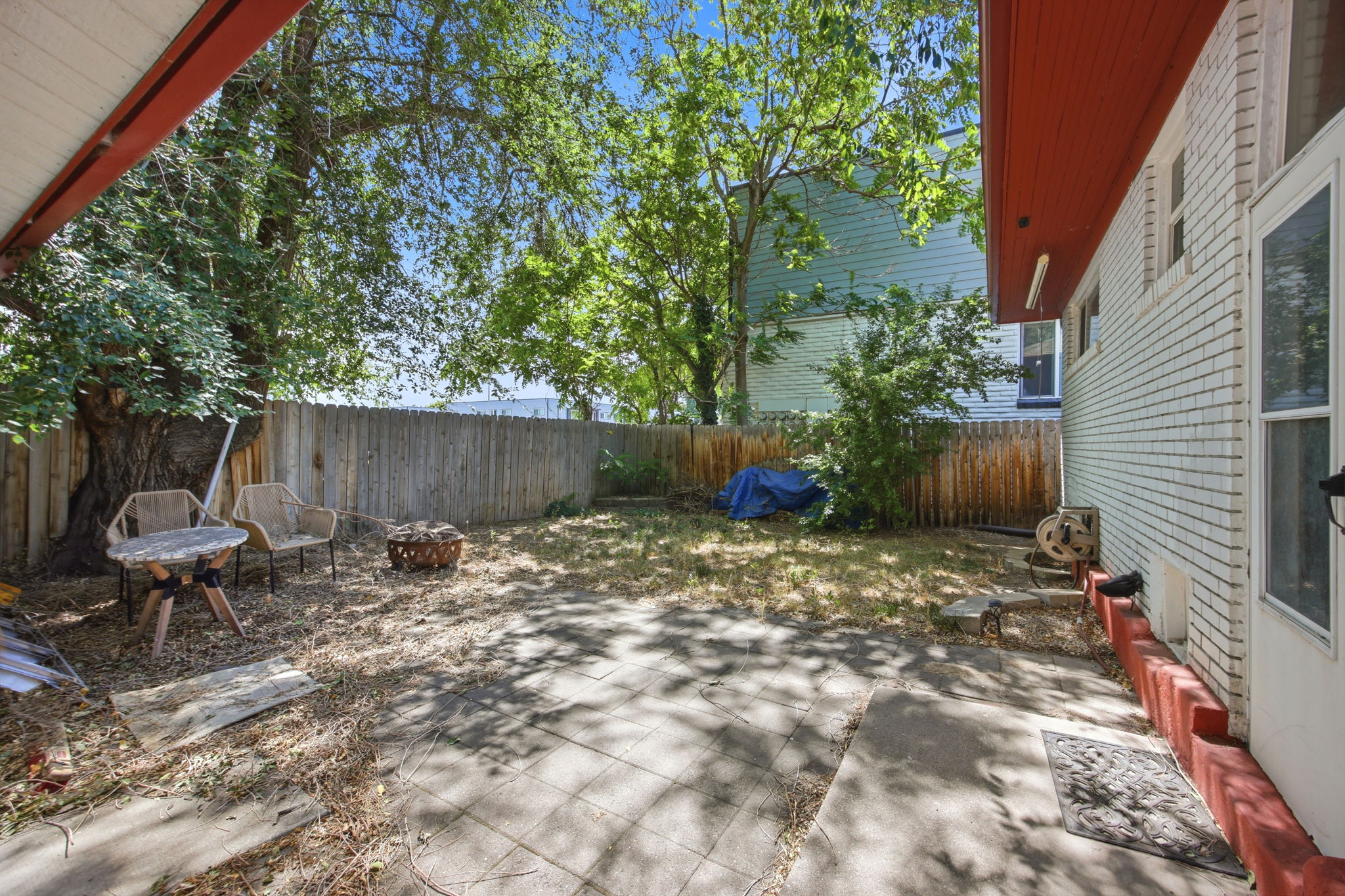 Backyard featuring a privacy fence, mature trees, and a concrete patio space