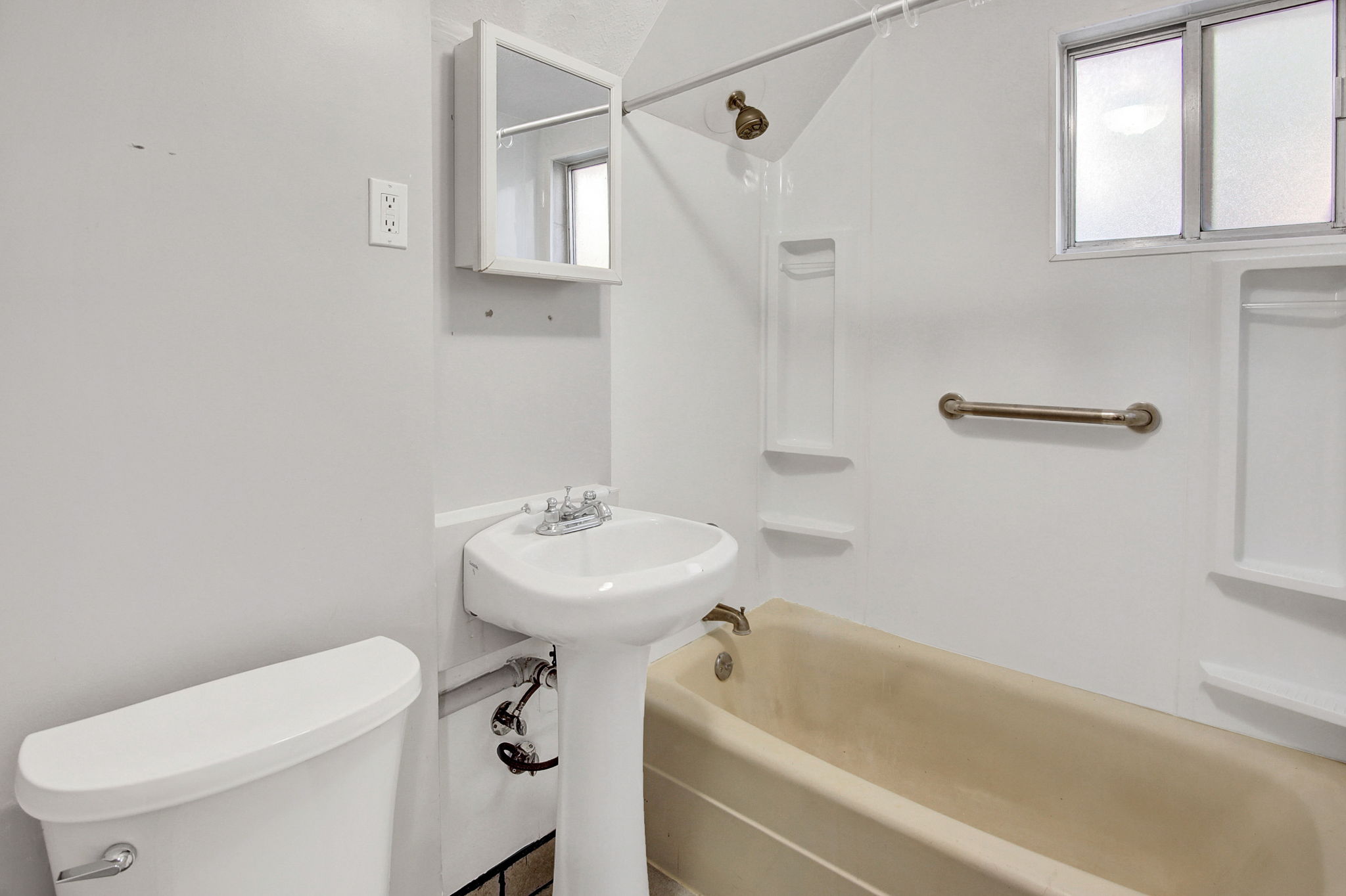 Bathroom featuring a pedestal sink, a toilet, a bathtub with an integrated shower, and a medicine cabinet