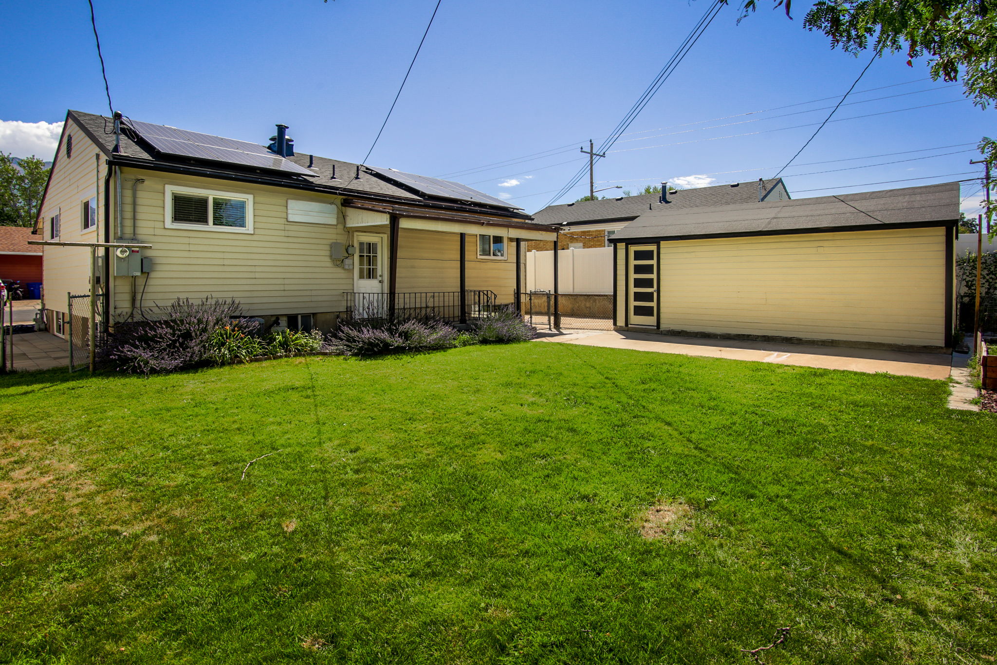 Expansive green lawn with a detached garage featuring a pedestrian door with vertical window panels