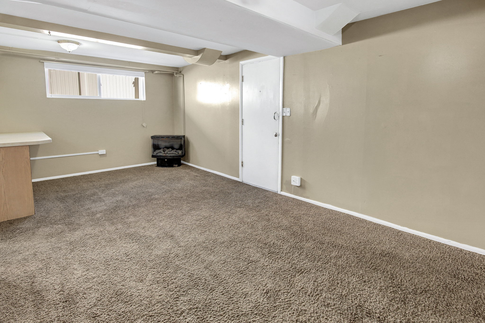 Carpeted room with a wall-mounted electric fireplace and a white door
