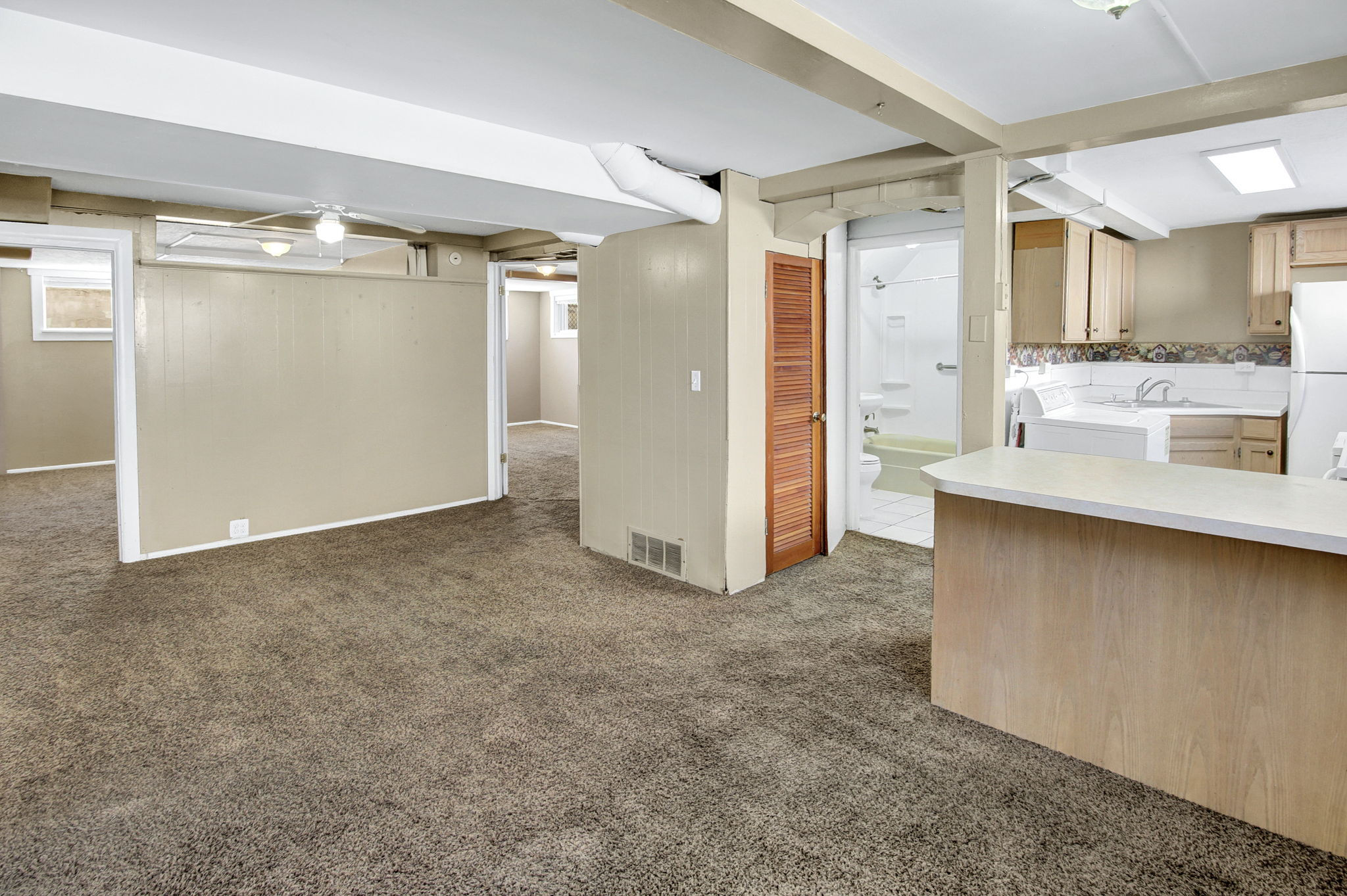 Spacious carpeted area with exposed ceiling beams and recessed lighting