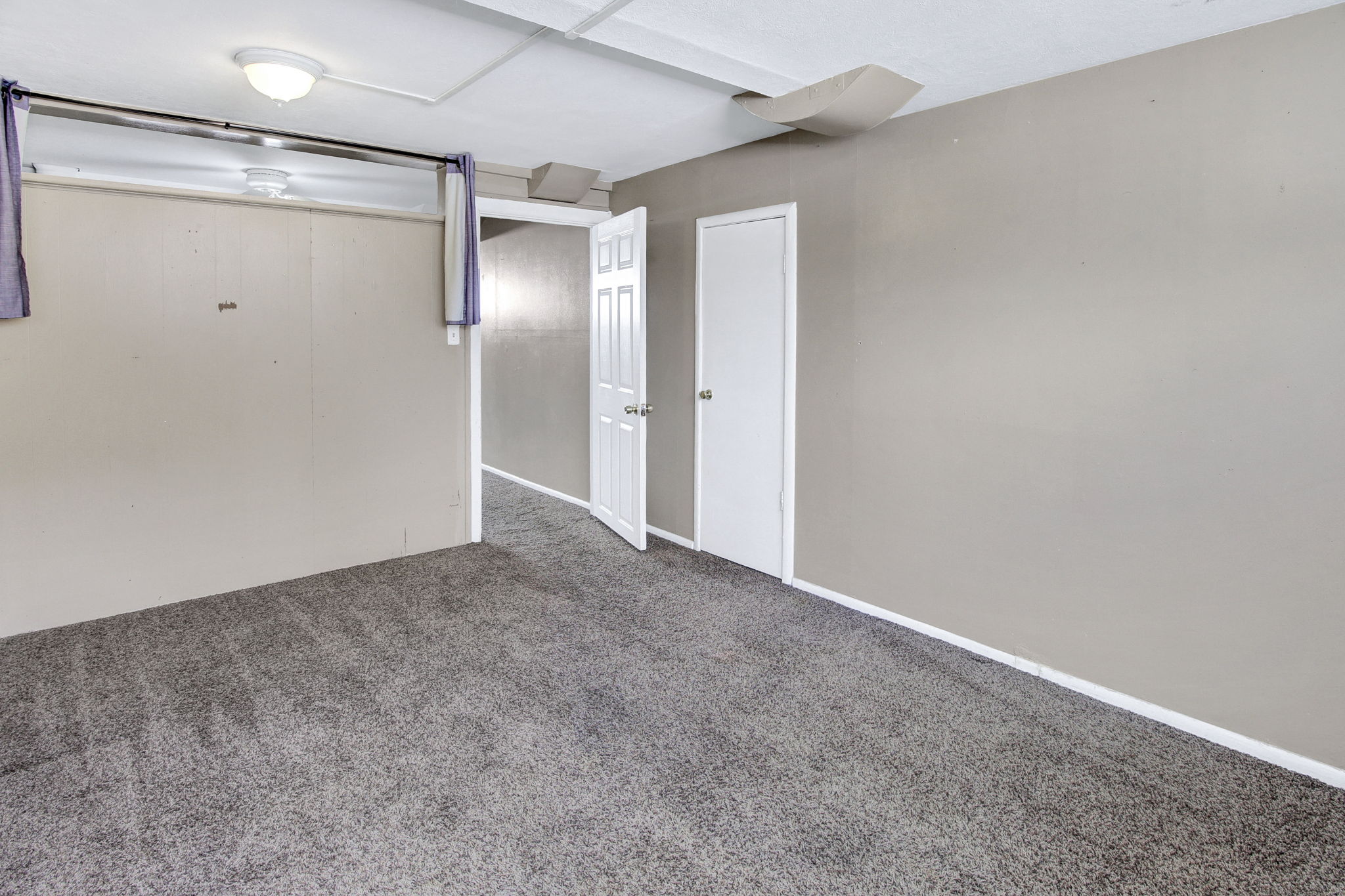 Spacious room featuring gray carpet, light neutral wall paint, and white trim