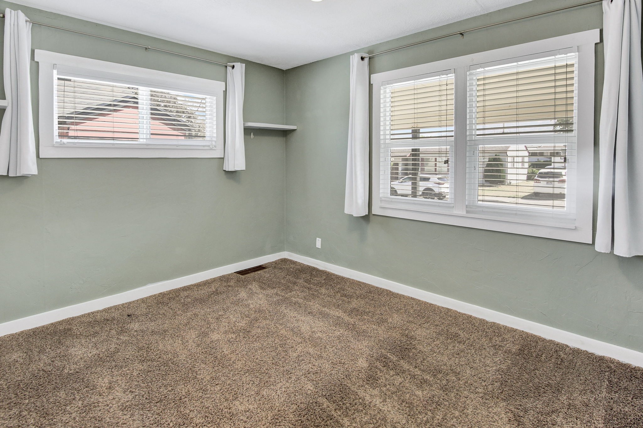 Interior space featuring wall-to-wall carpeting, light green wall finishes, white trim, and two windows with white blinds