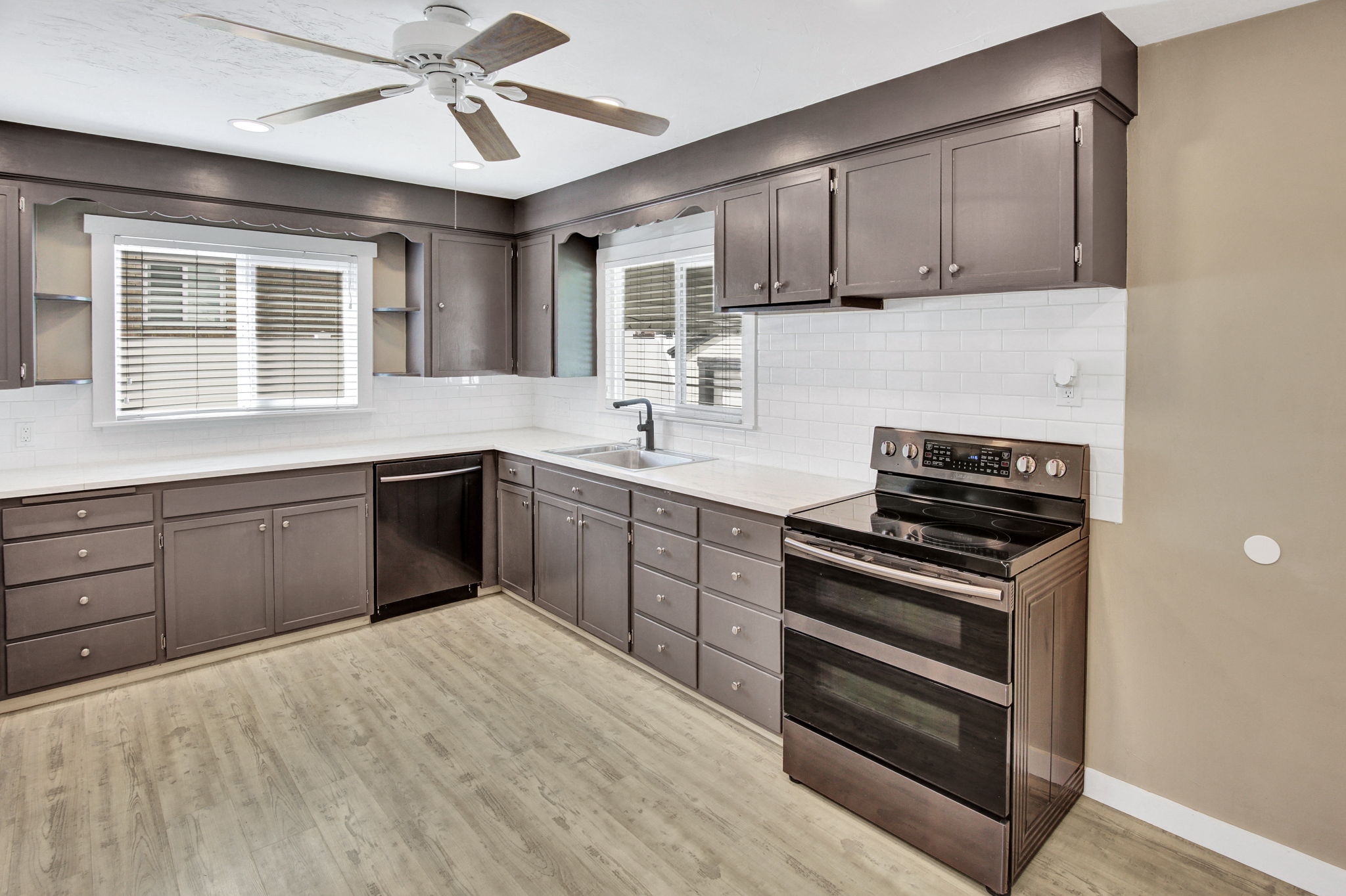 Kitchen featuring extensive cabinetry, white subway tile backsplash, stainless steel appliances, and wood-finish flooring