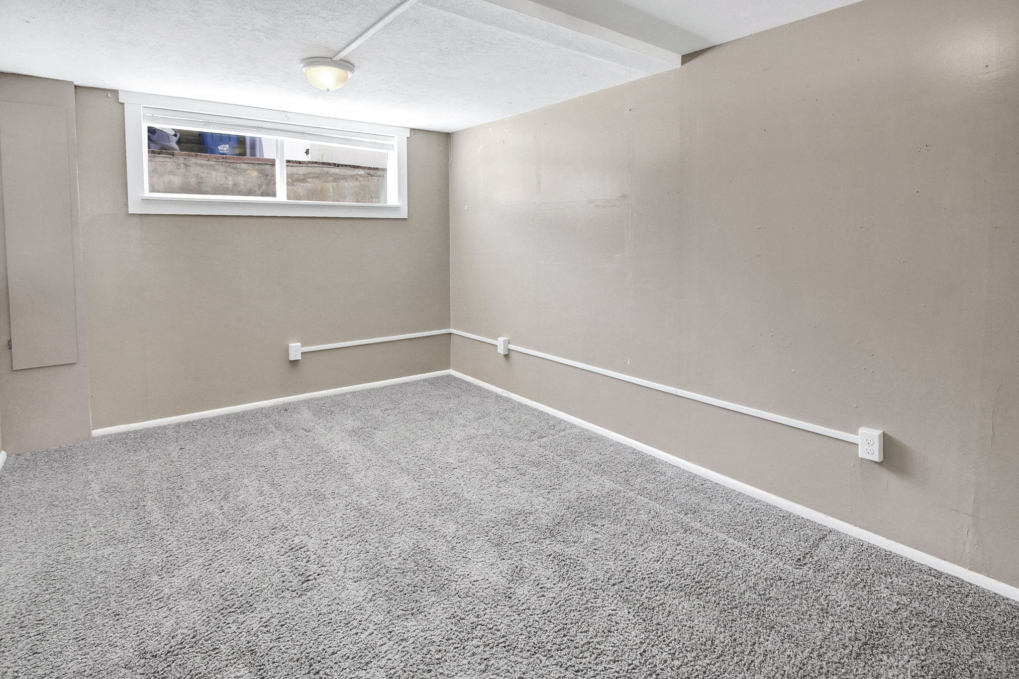 Carpeted room with a flush-mount ceiling light and a single window