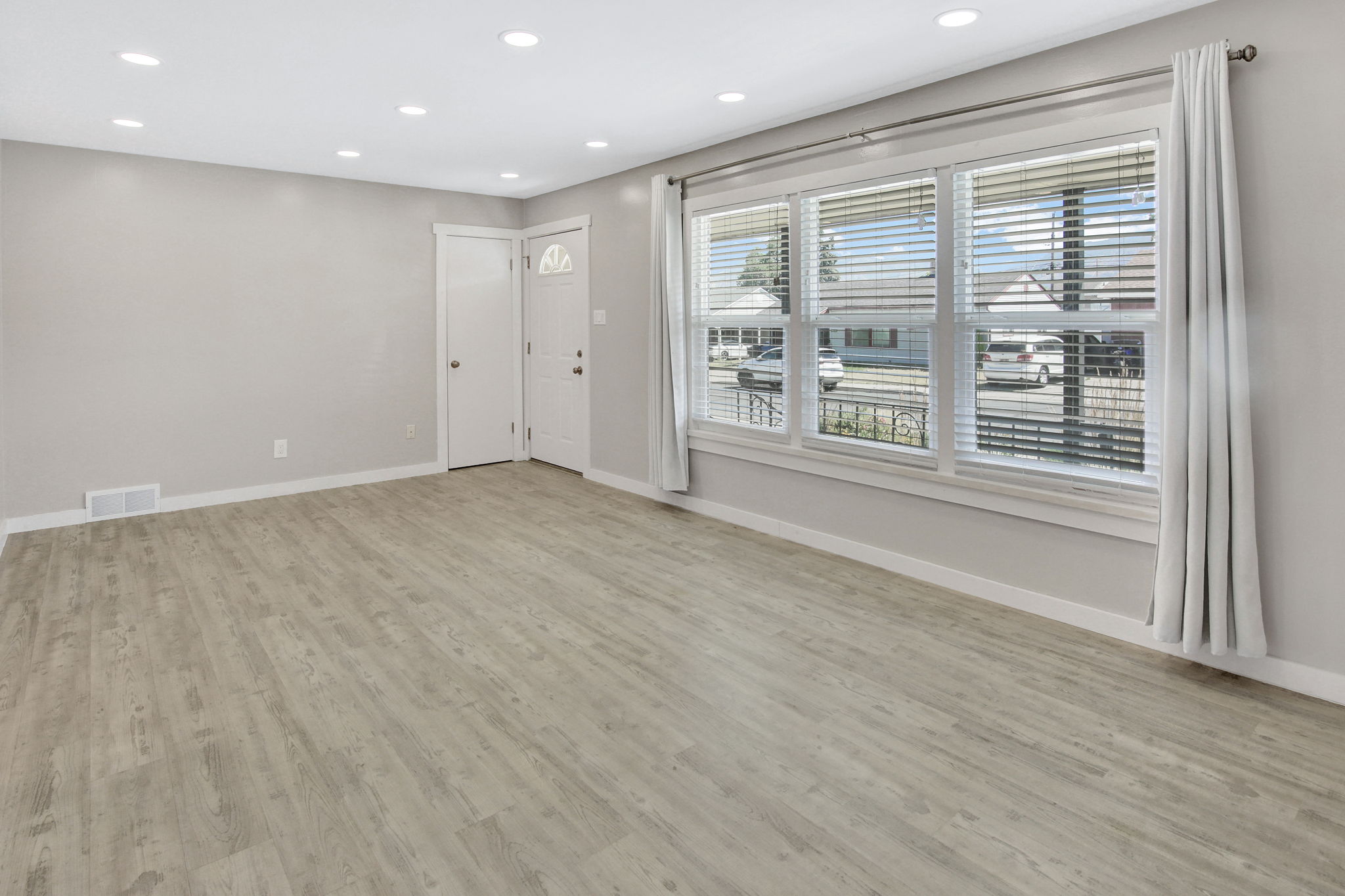 Living area featuring wood-finish flooring, recessed lighting, and a front entry door with a decorative glass insert