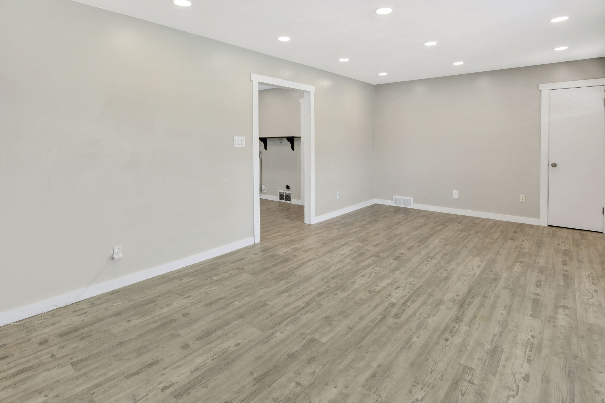 Spacious room featuring wood-finish flooring, recessed lighting, neutral paint, and white trim