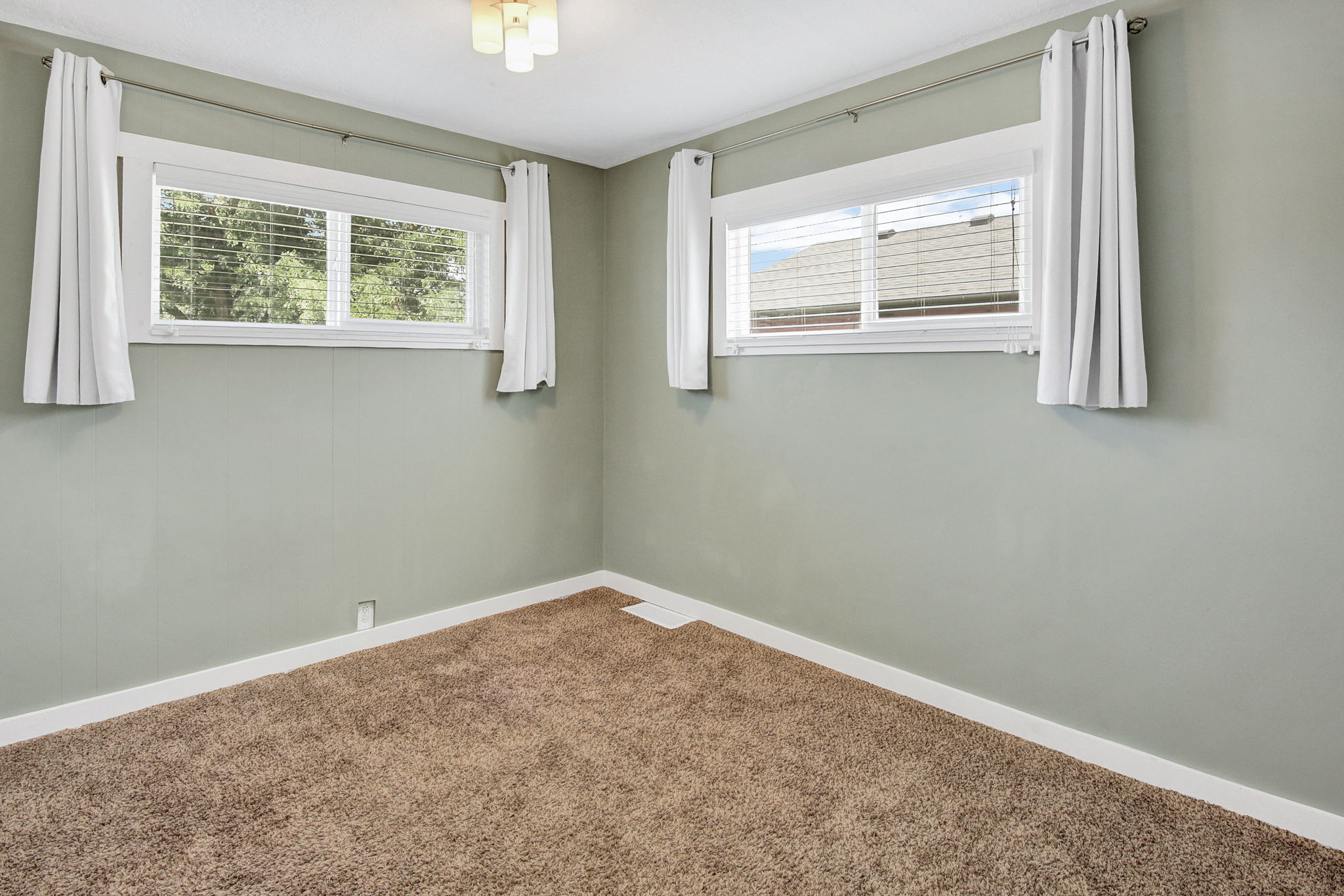 Interior room featuring two windows, neutral wall tones, and brown carpet flooring
