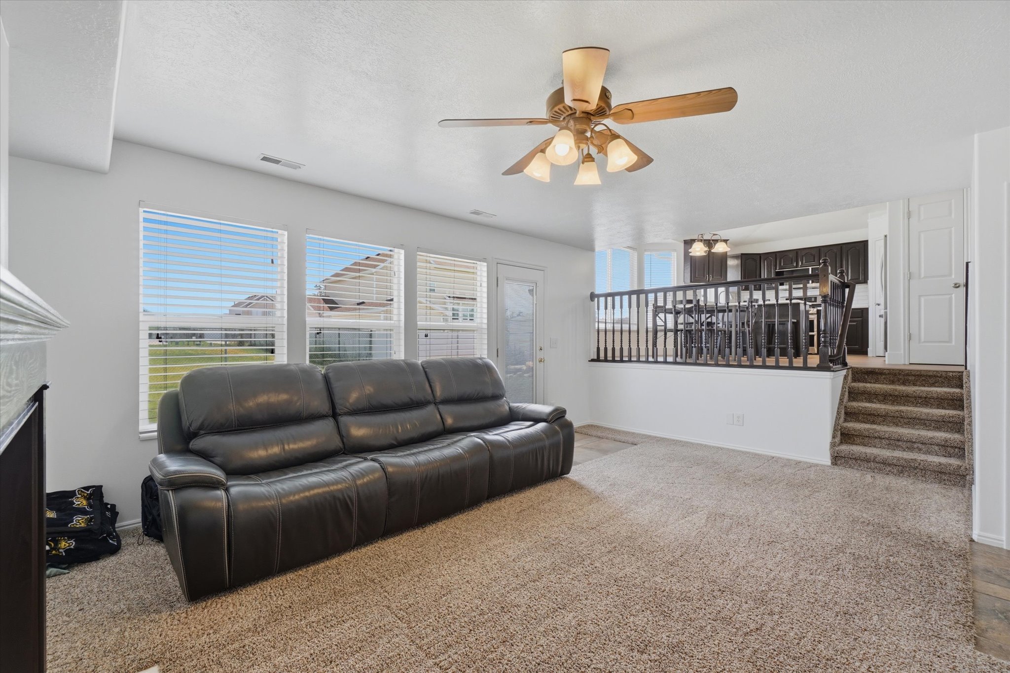 Spacious living area featuring neutral carpeting and a ceiling fan