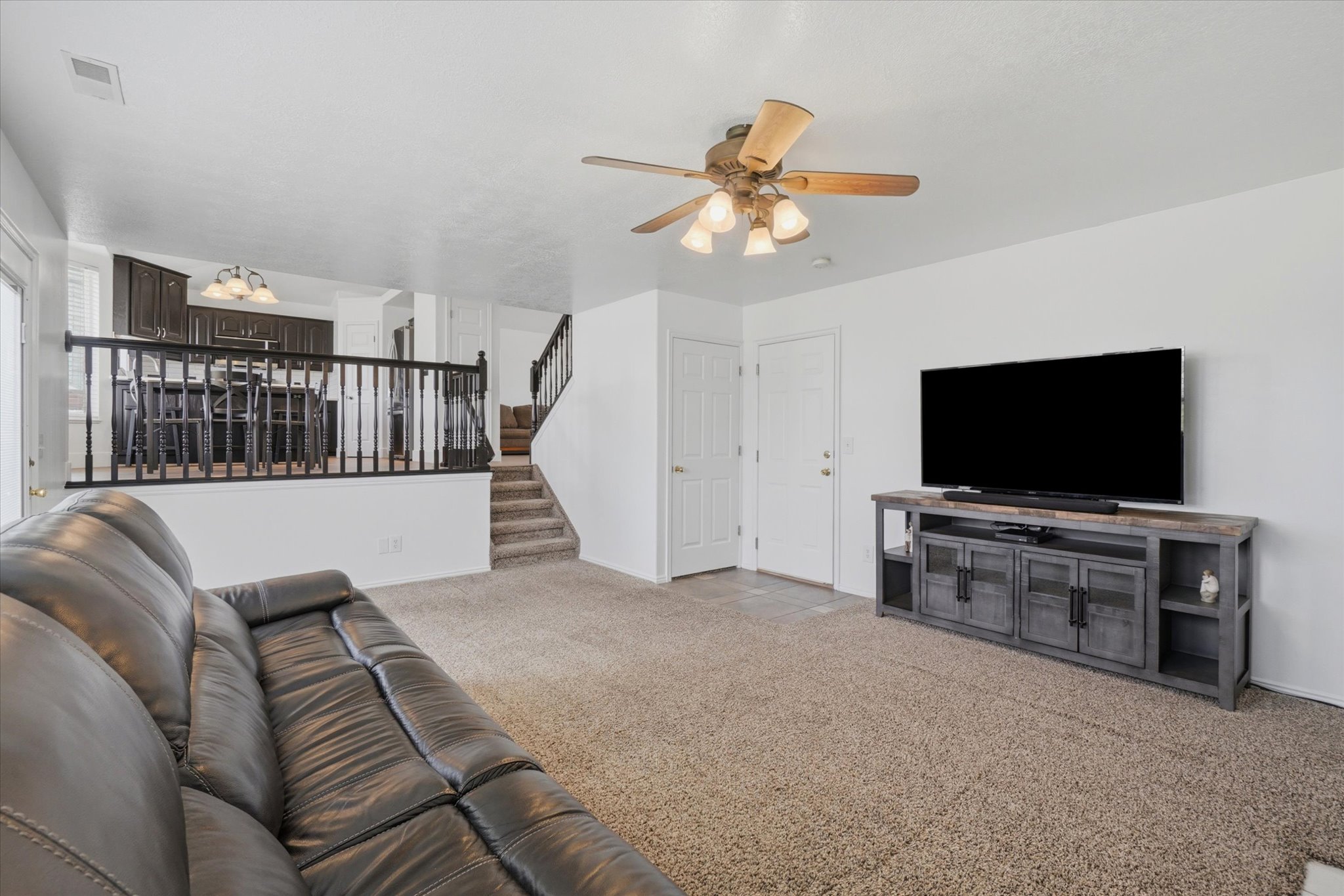 Spacious living area featuring neutral carpet flooring and a ceiling fan with integrated lighting