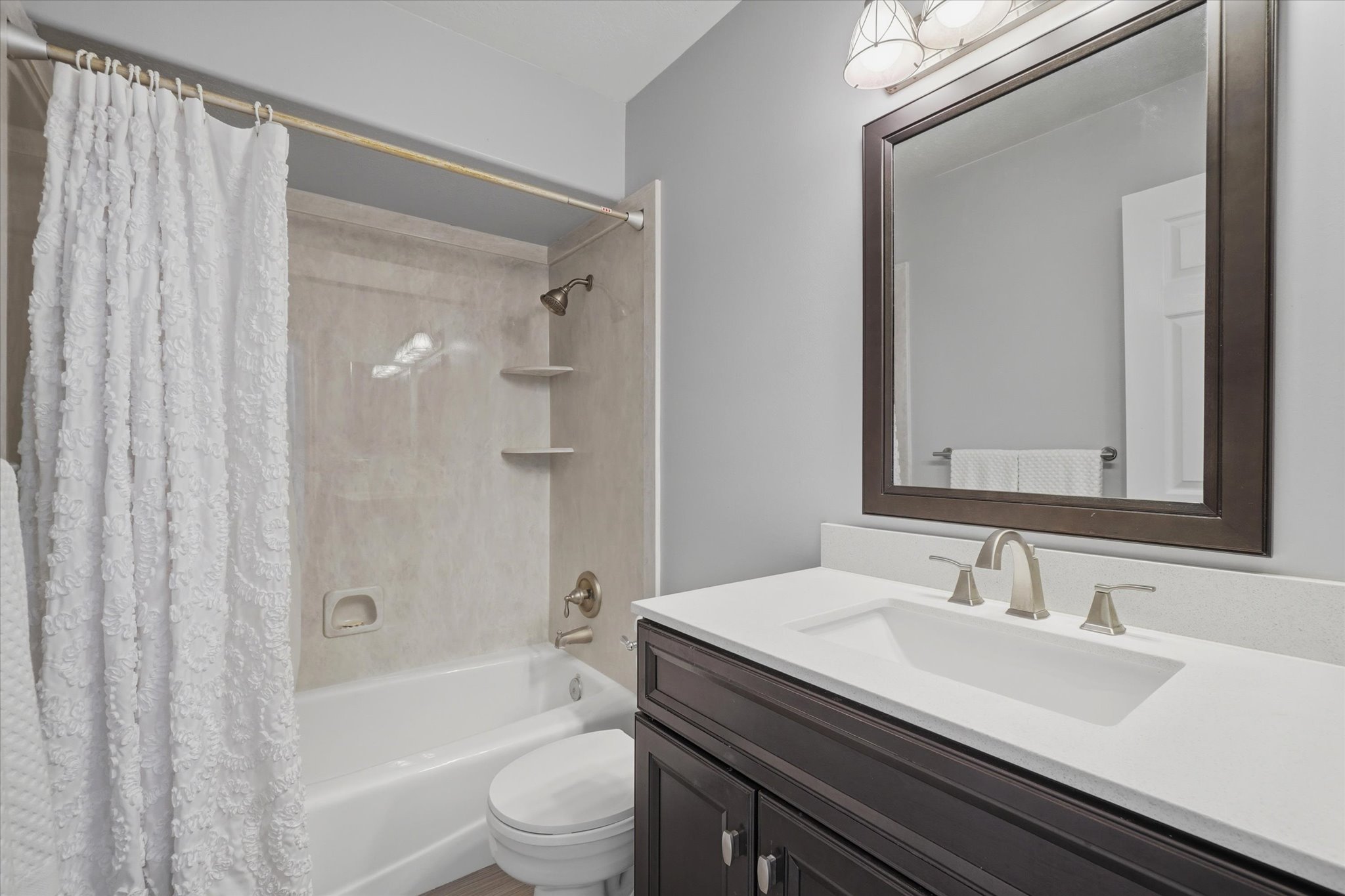 Remodeled Bathroom featuring a built-in tub with shower, integrated shelving, and a vanity and sink