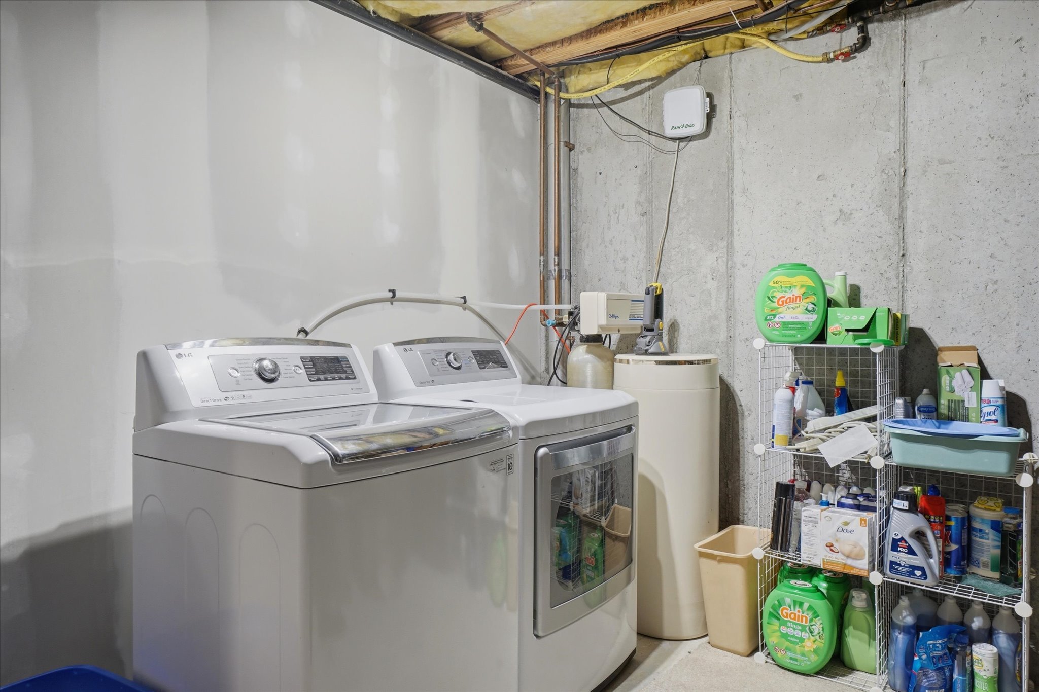 Dedicated laundry area featuring a washer and dryer, exposed ceiling joists, and concrete walls