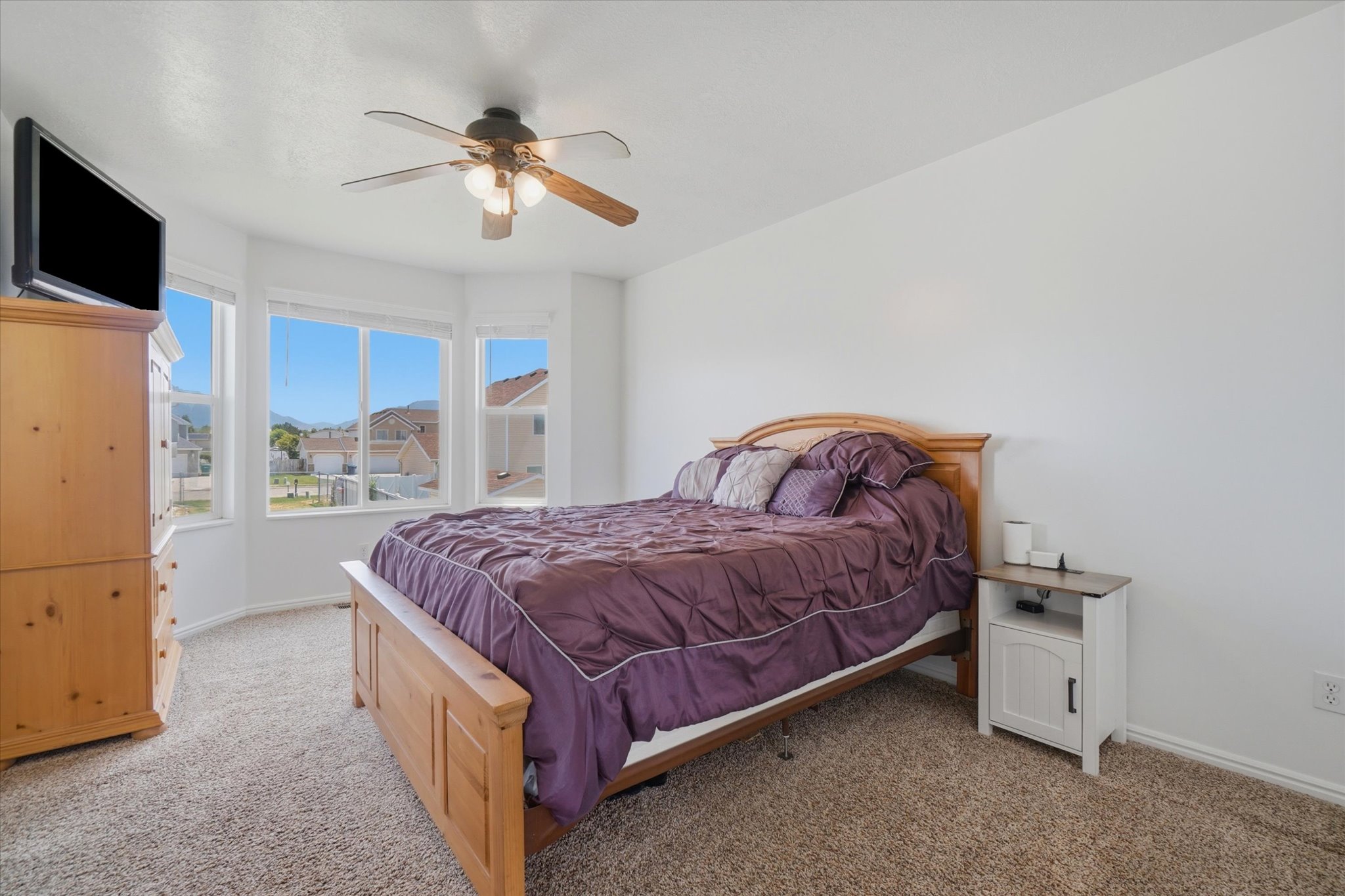 Primary bedroom with boxed windows and ceiling fan