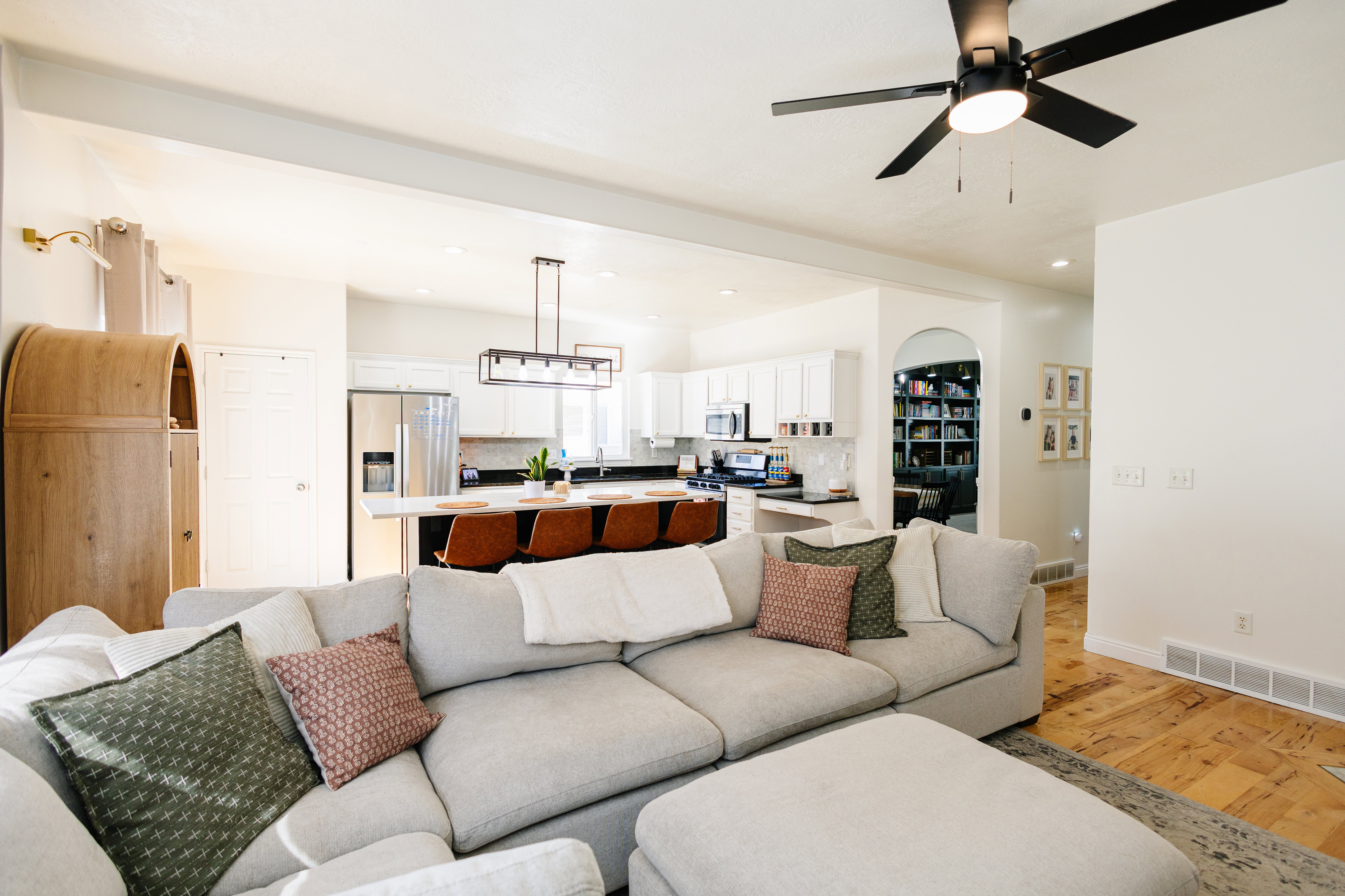 Open-concept living space featuring a ceiling fan, light wood-finish flooring, and white walls