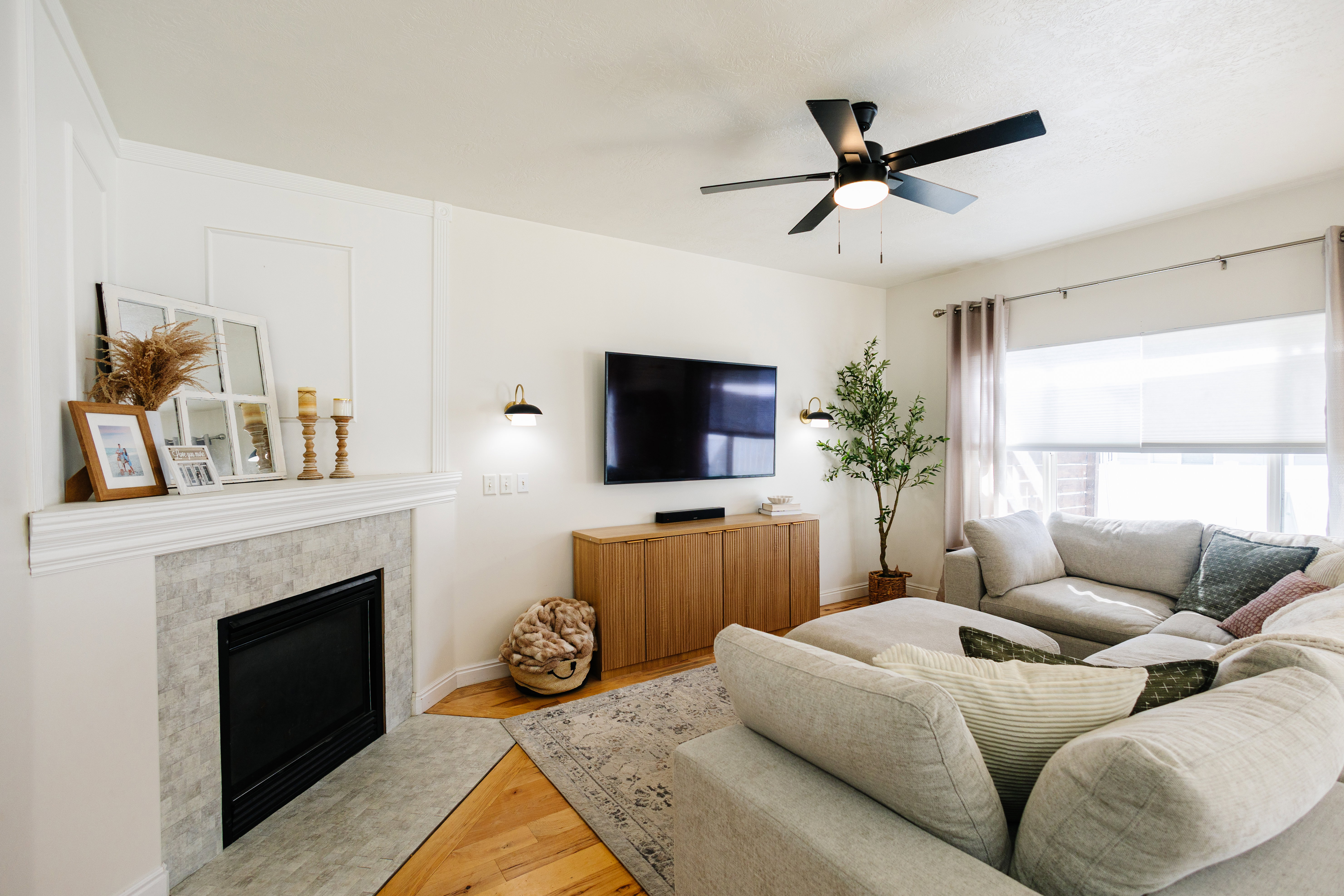 Living area featuring a tiled fireplace with a white mantel, light wood-finish flooring, recessed wall lighting, and a ceiling fan