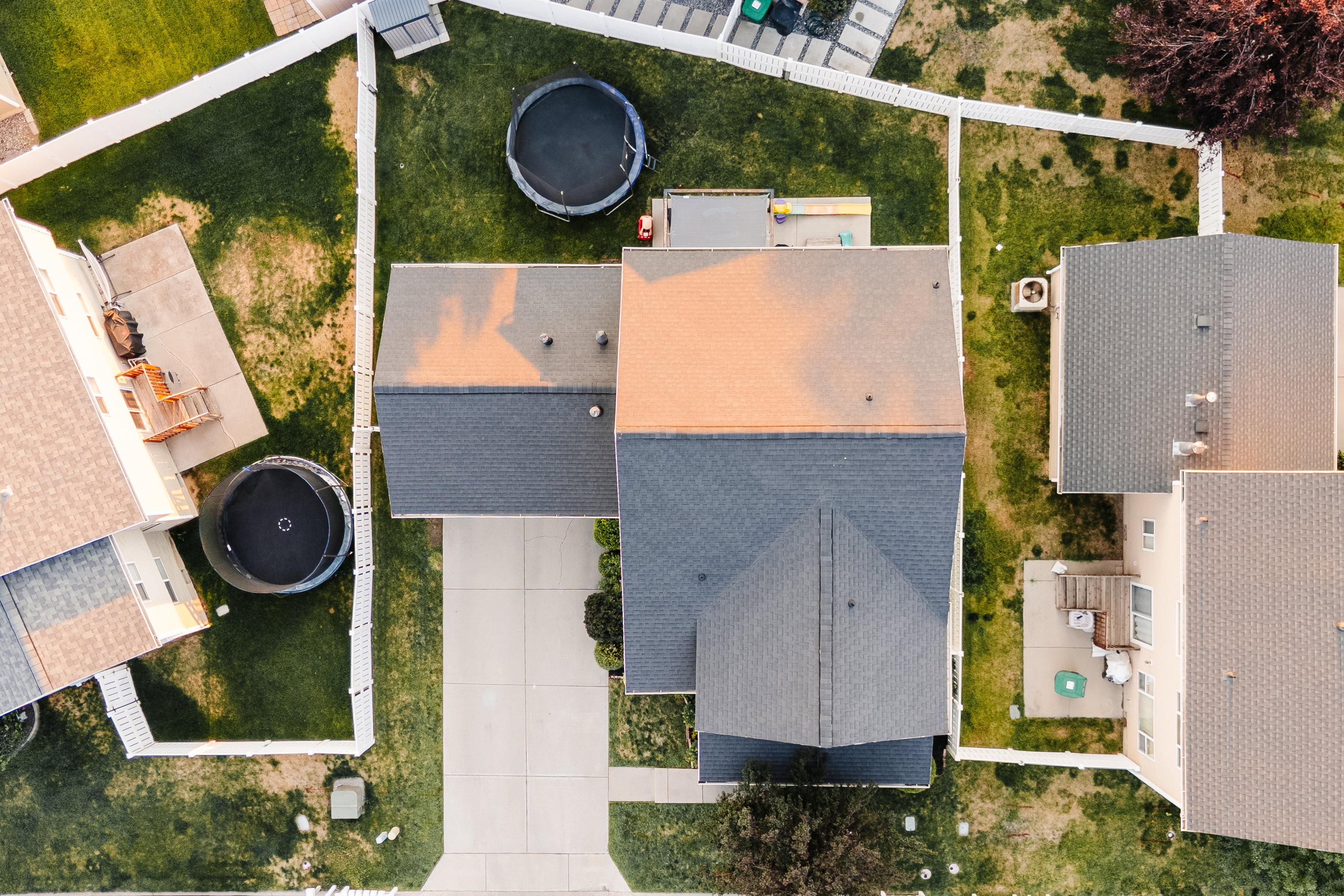 Aerial view showcasing a property with a driveway, distinct roofline, and fenced perimeter