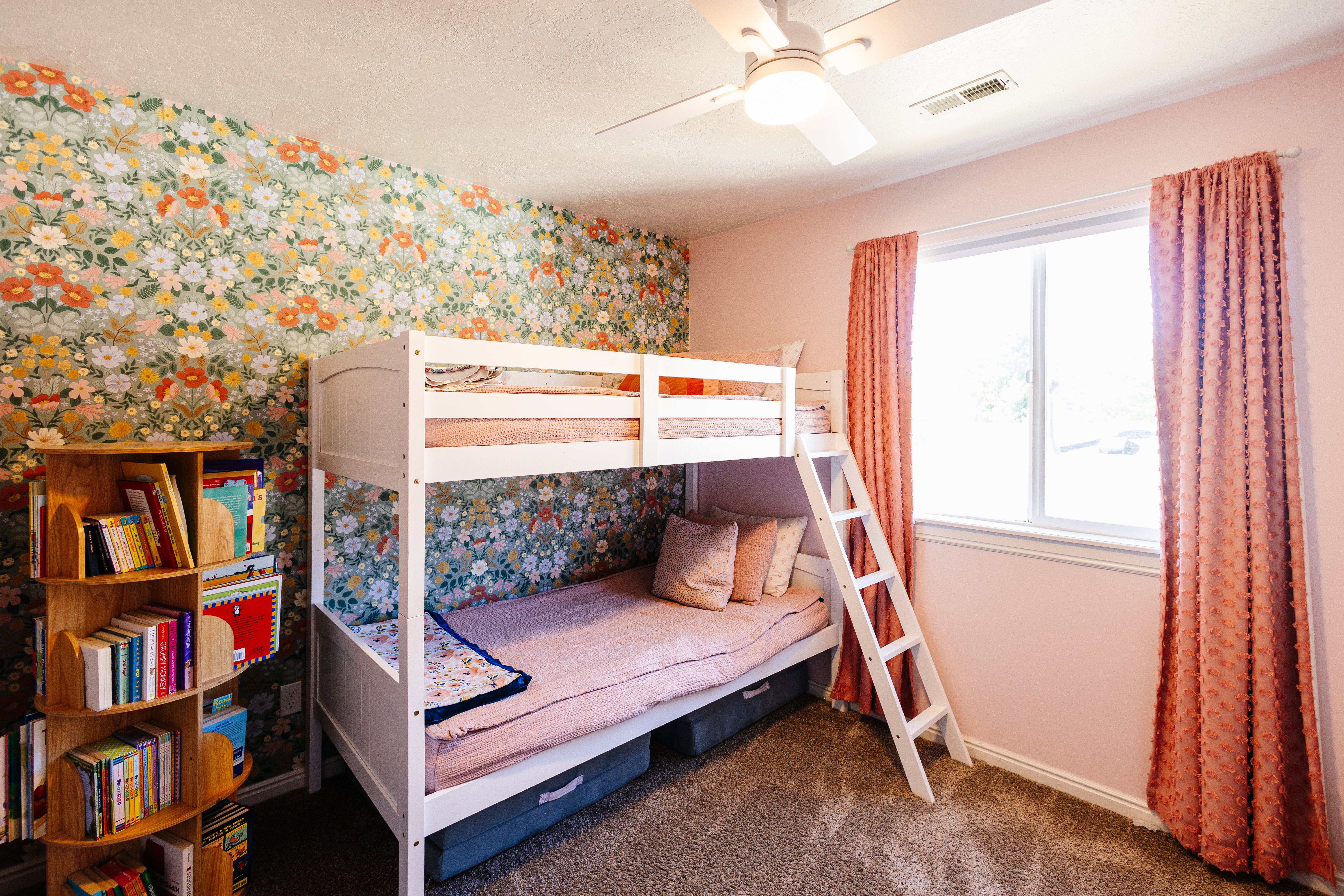 Carpeted room featuring a floral accent wall and a ceiling fan