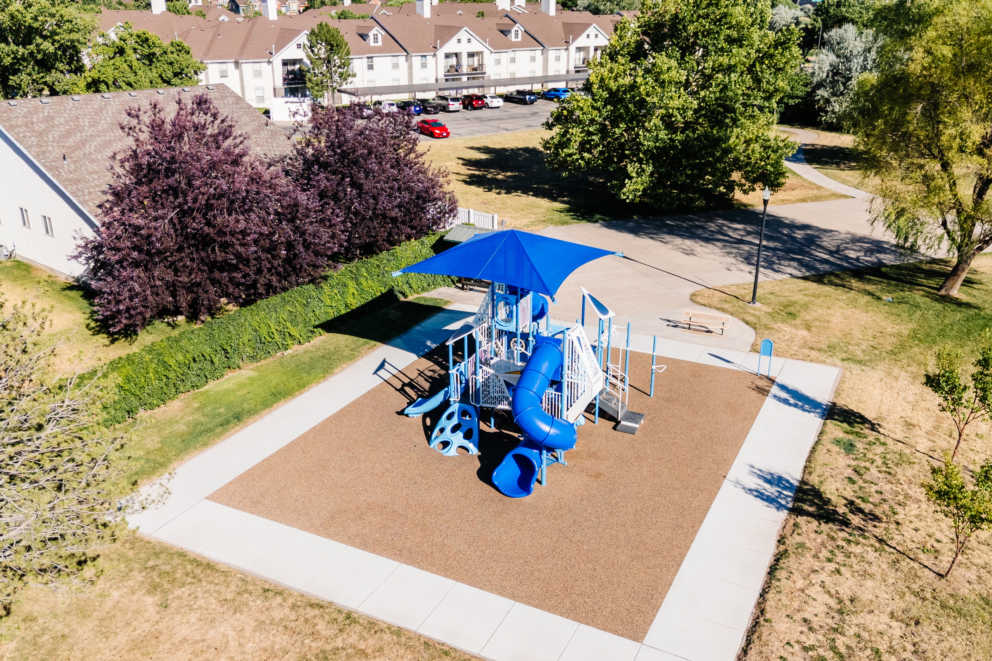 Recreational playground featuring a blue shade canopy, slide, climbing structures, and protective surfacing
