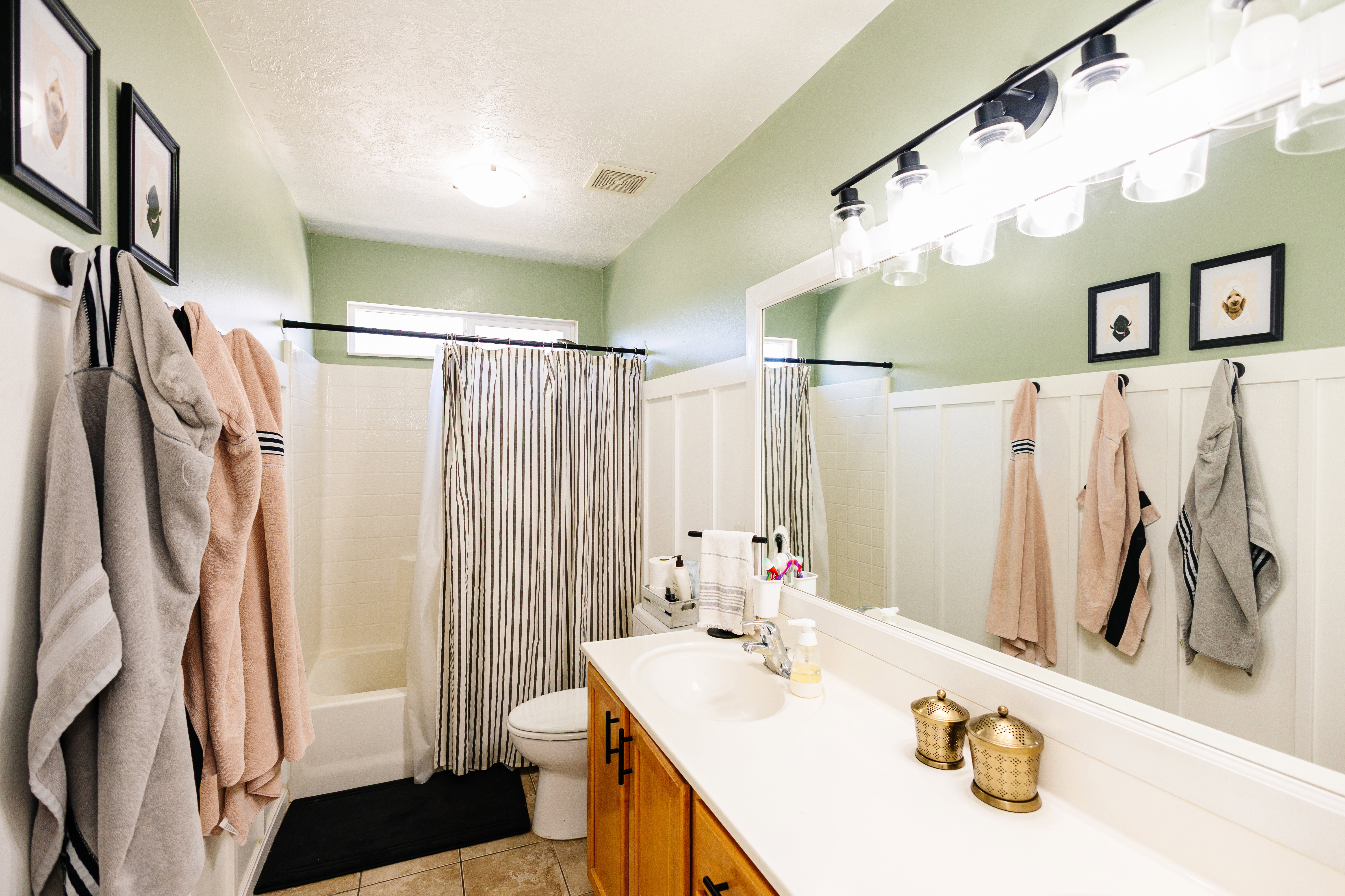 Bathroom featuring a full-width vanity mirror, a vanity with wood-finish cabinetry, and a shower-tub combination