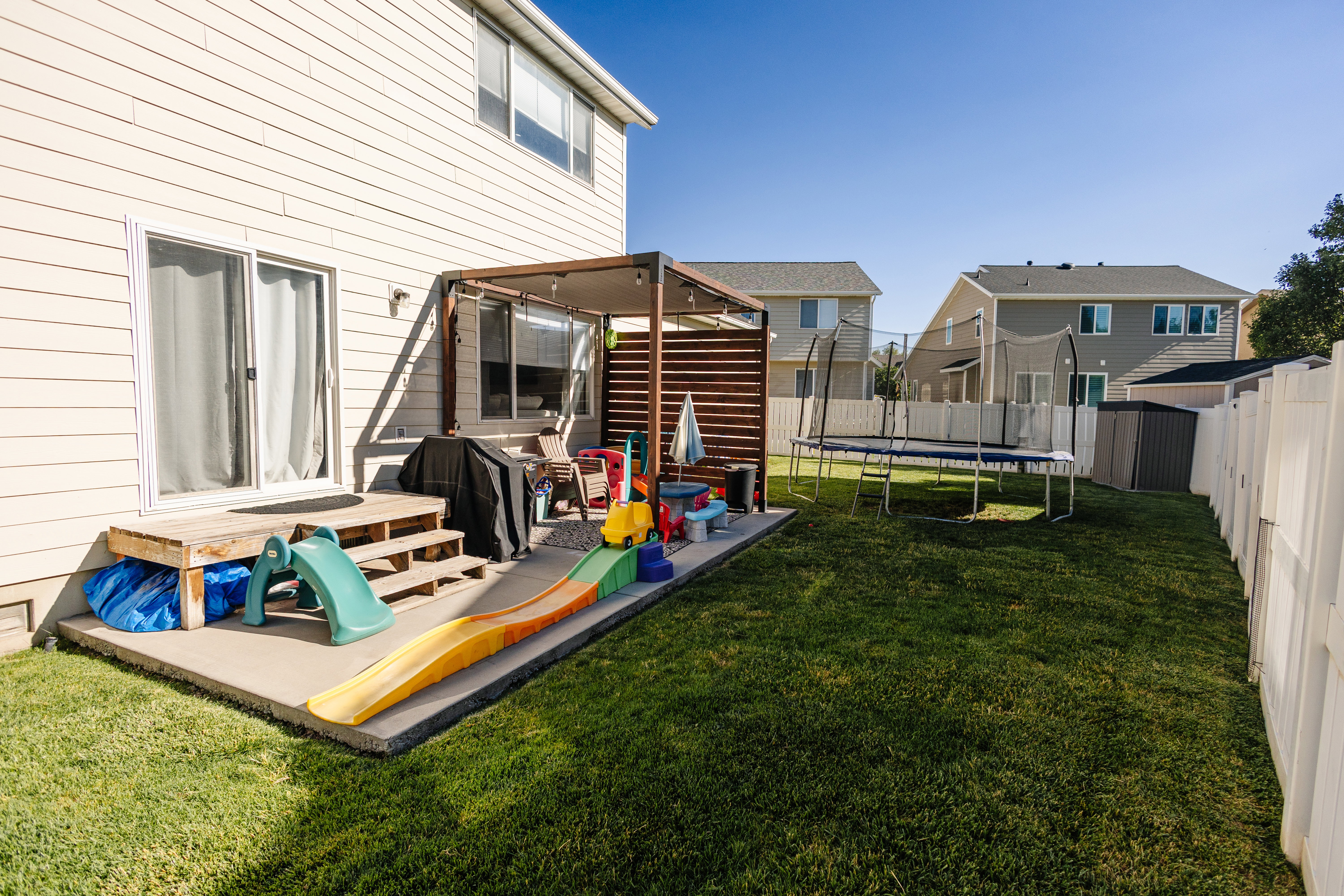 Expansive backyard featuring a manicured lawn, a concrete patio area, and a privacy fence