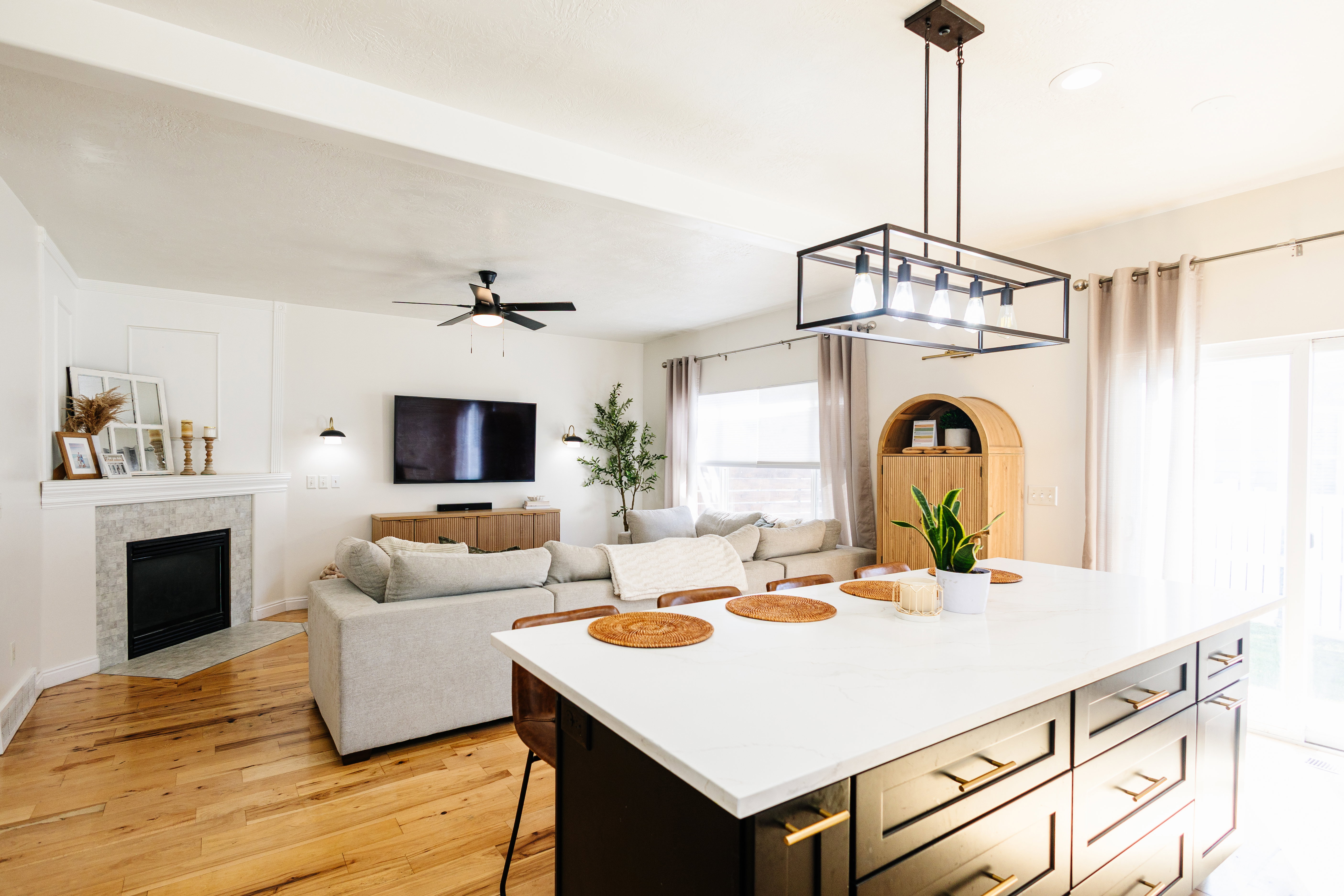 Spacious kitchen island with a white countertop and dark cabinetry, illuminated by a modern rectangular chandelier