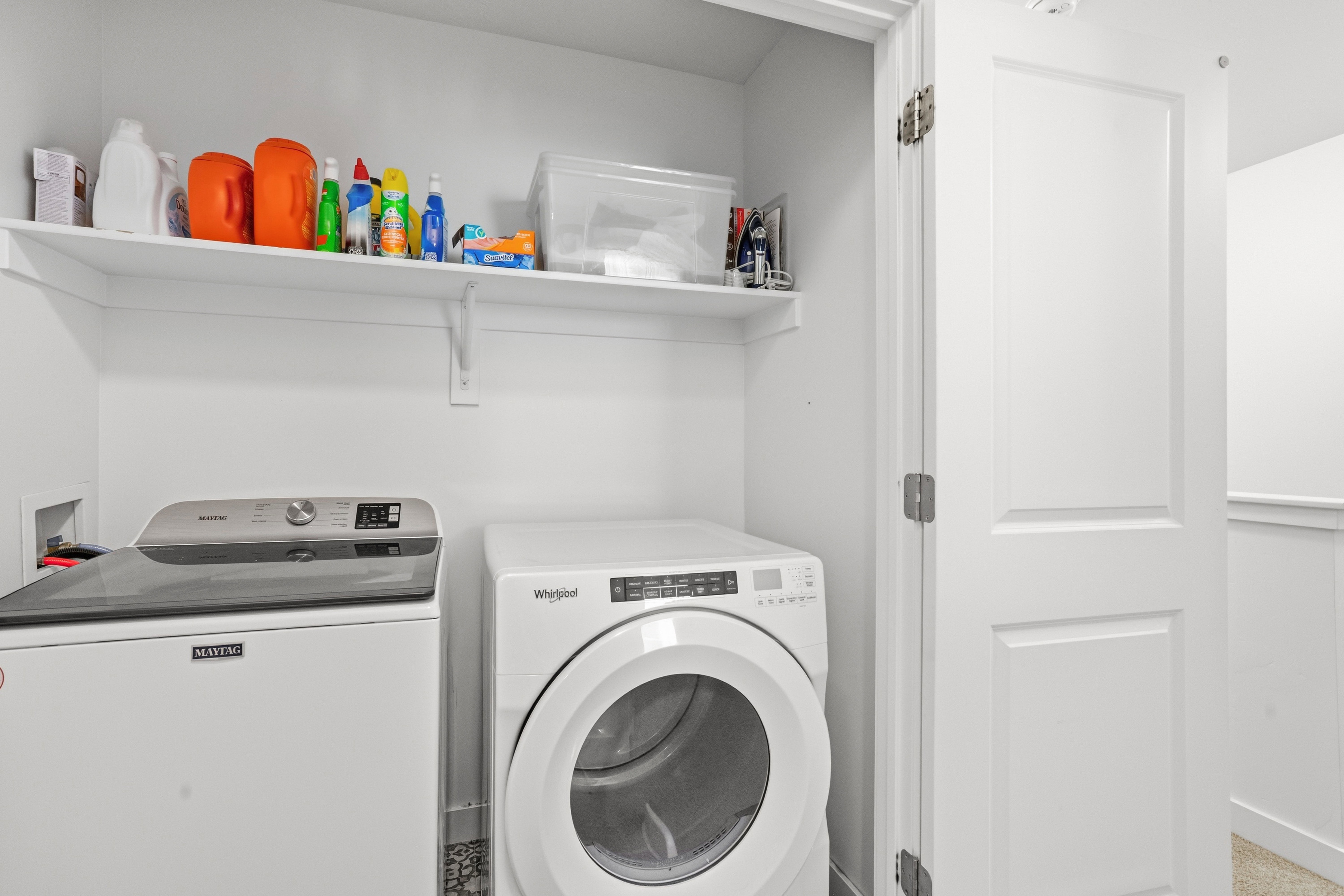 Dedicated laundry space featuring a white top-load washer, a white front-load dryer, and an overhead storage shelf