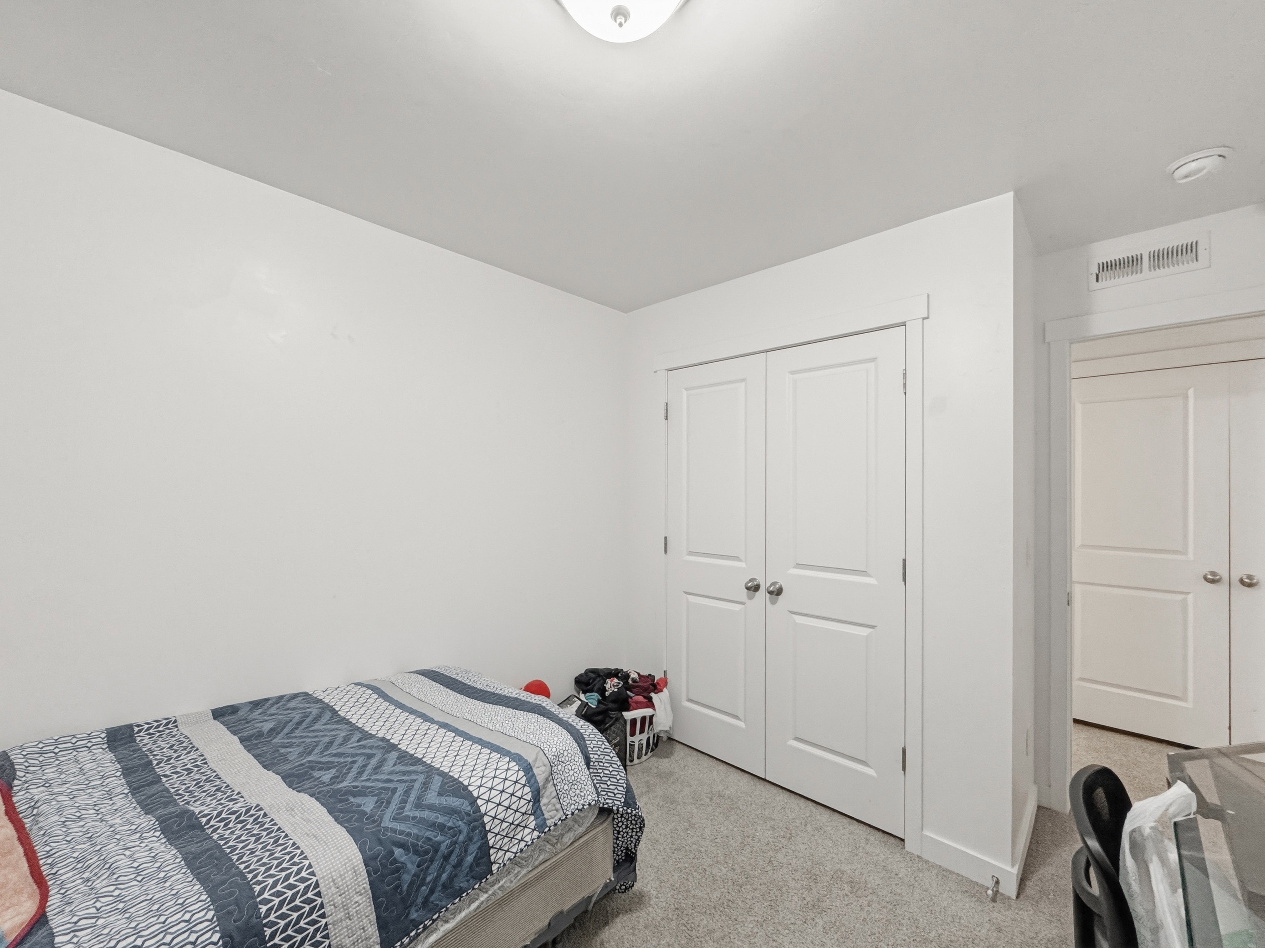 Room featuring neutral wall paint, light-colored carpet, a flush-mount ceiling light fixture, and a white bi-fold closet