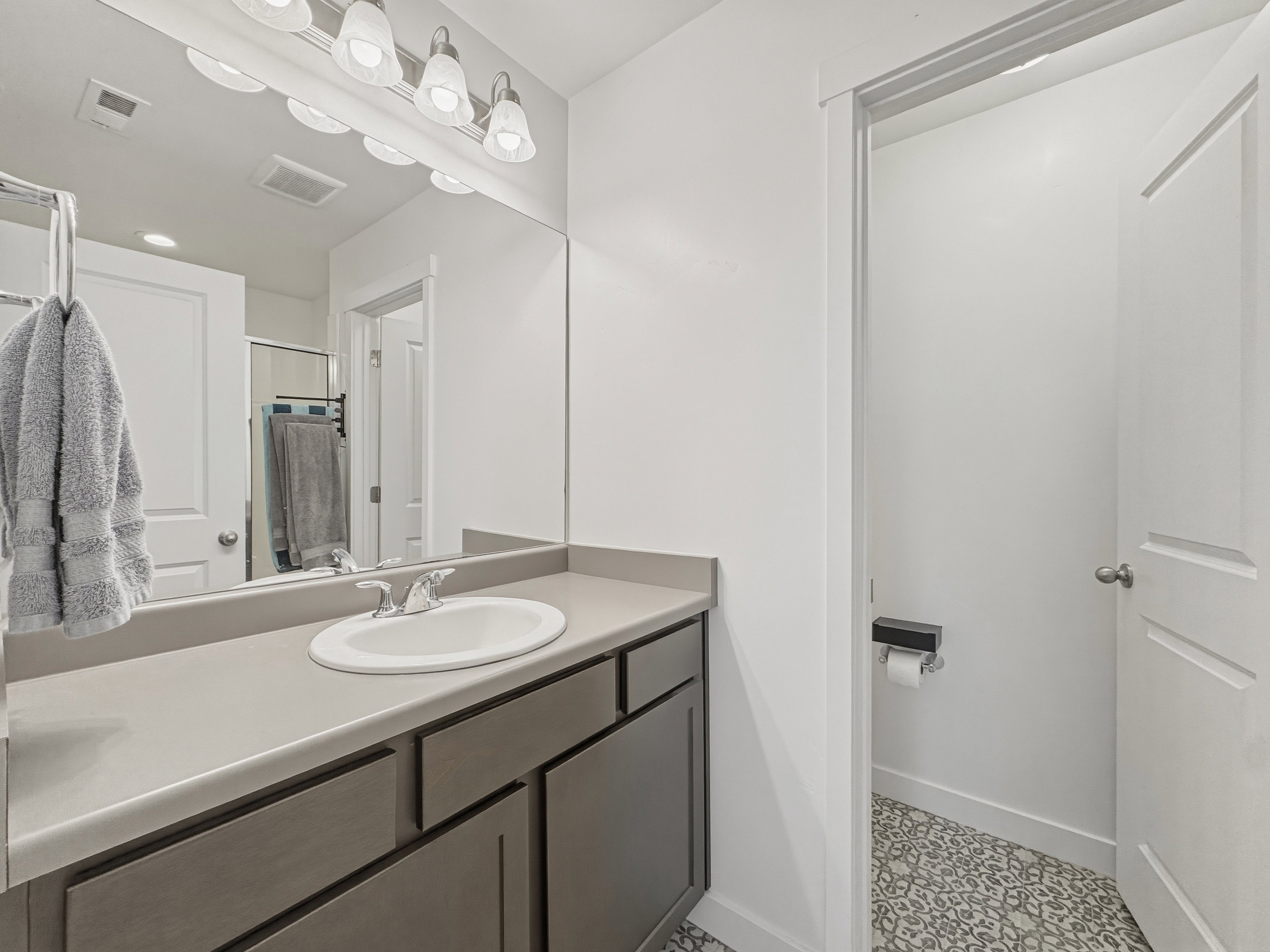 Bathroom vanity featuring a single basin sink, chrome faucet, and expansive countertop