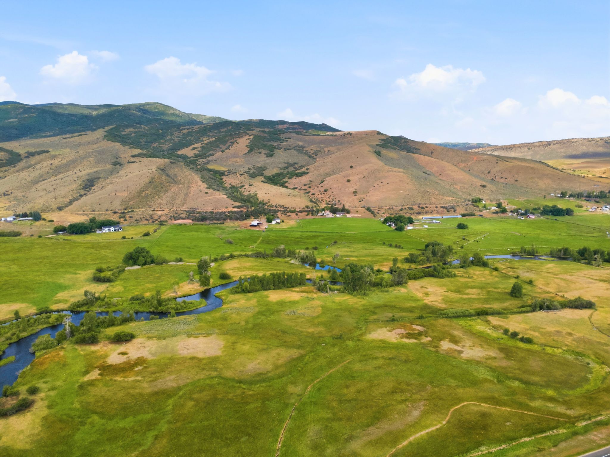 Expansive green fields featuring a winding river and scattered trees