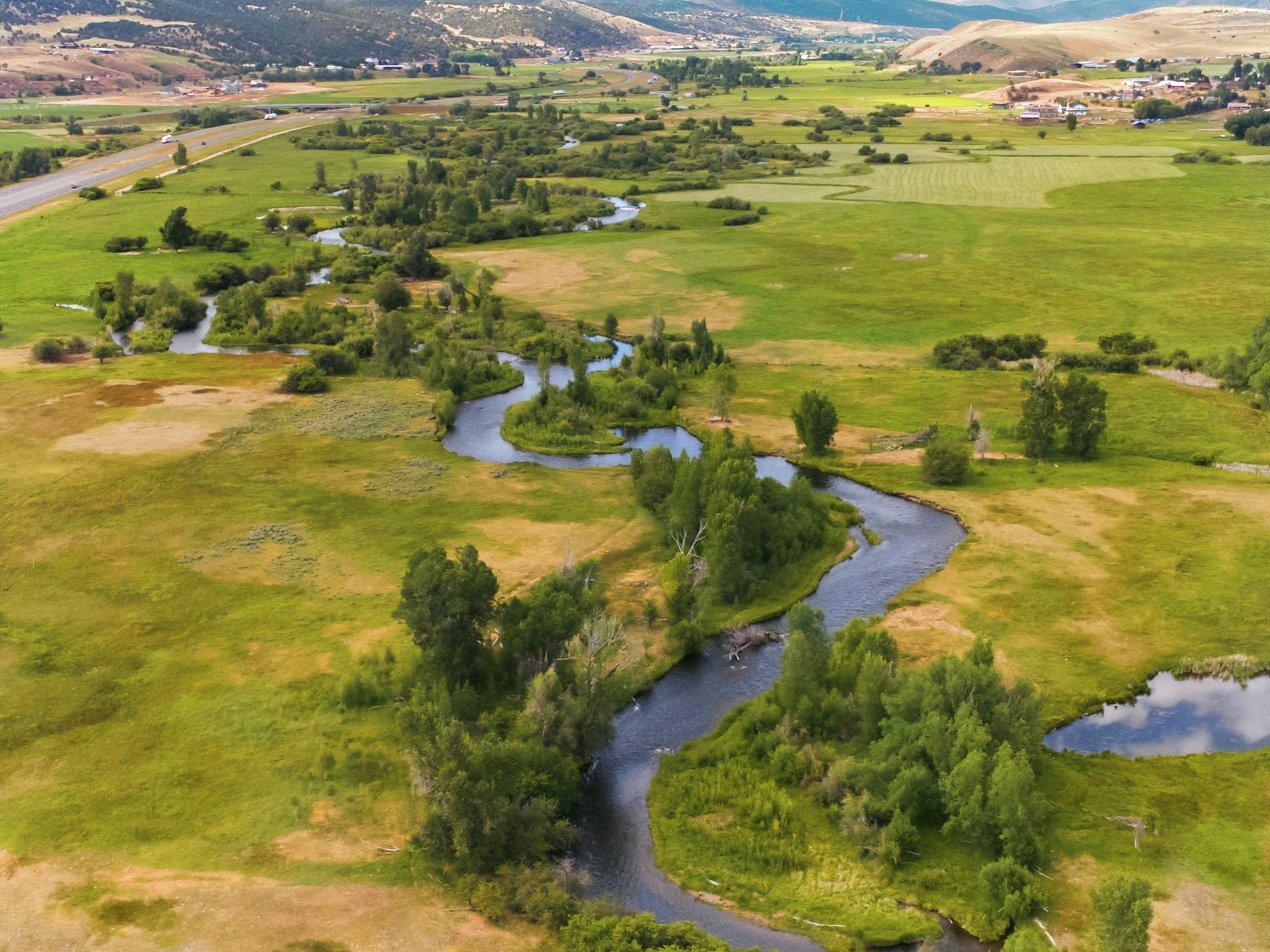 Meandering river winding through expansive green and golden fields