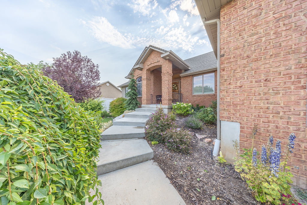 Brick exterior featuring an arched entryway, covered porch, and stepped concrete walkway