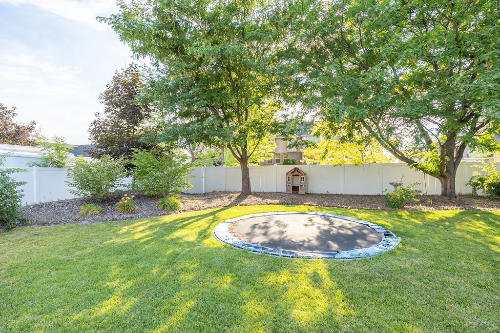 Expansive backyard featuring a lush lawn and mature trees