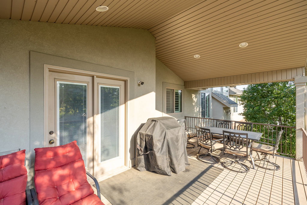 Covered outdoor patio featuring light-toned flooring, a protective railing, and recessed ceiling lighting